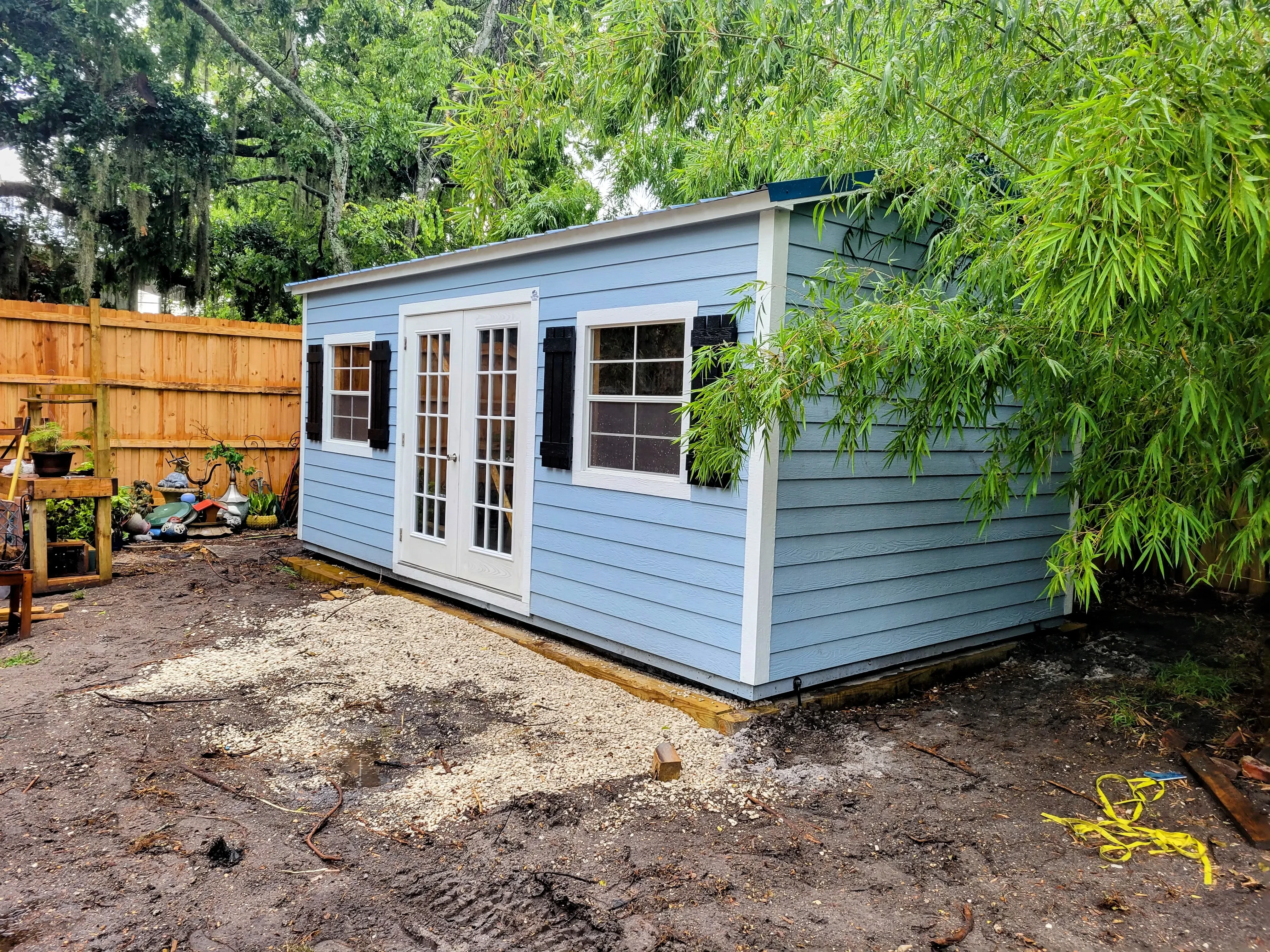 Blue lap siding shed with glass patio doors in the garden