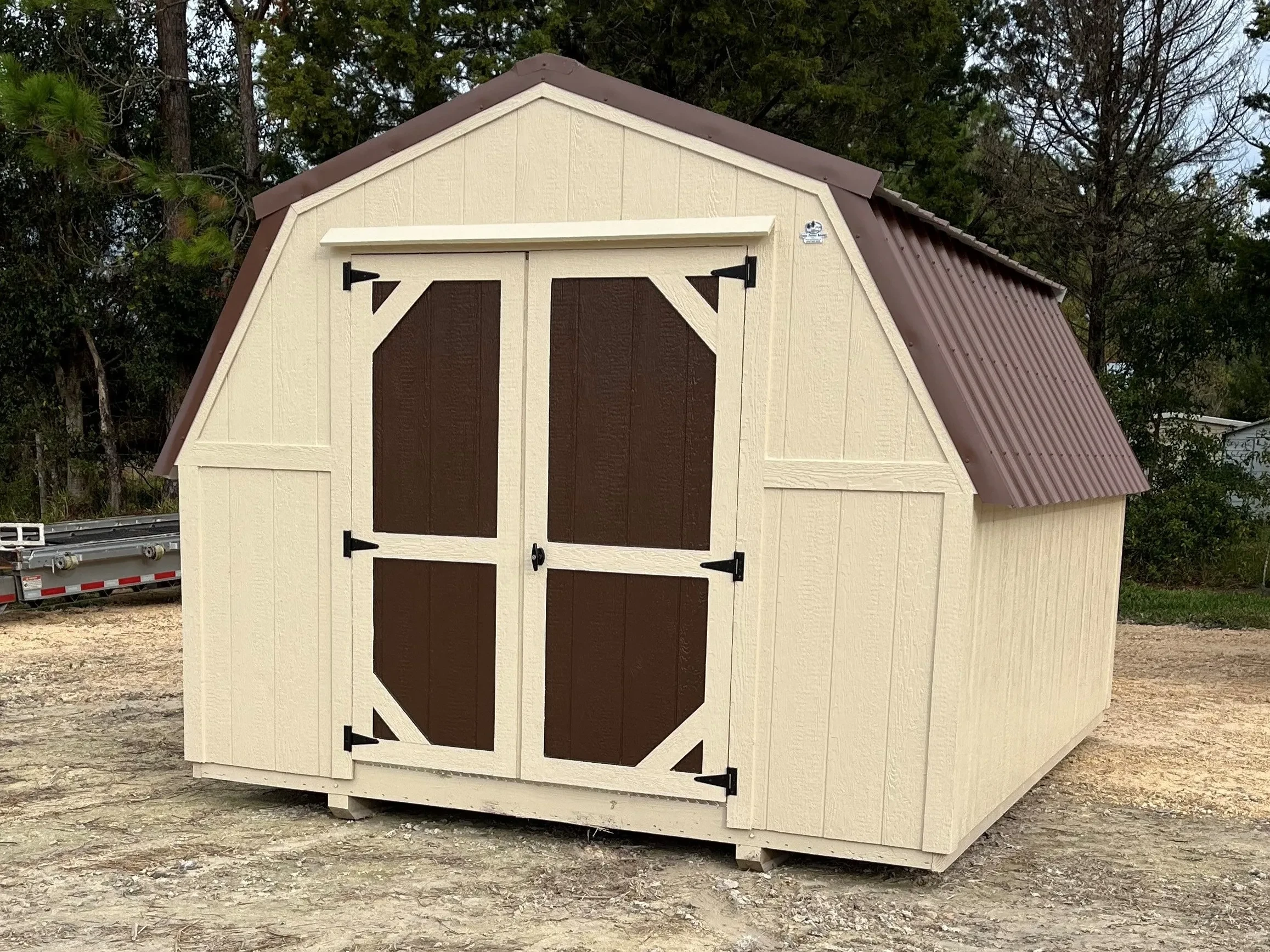 Exterior of an almond 10x12 barn economy with dark brown double wood doors
