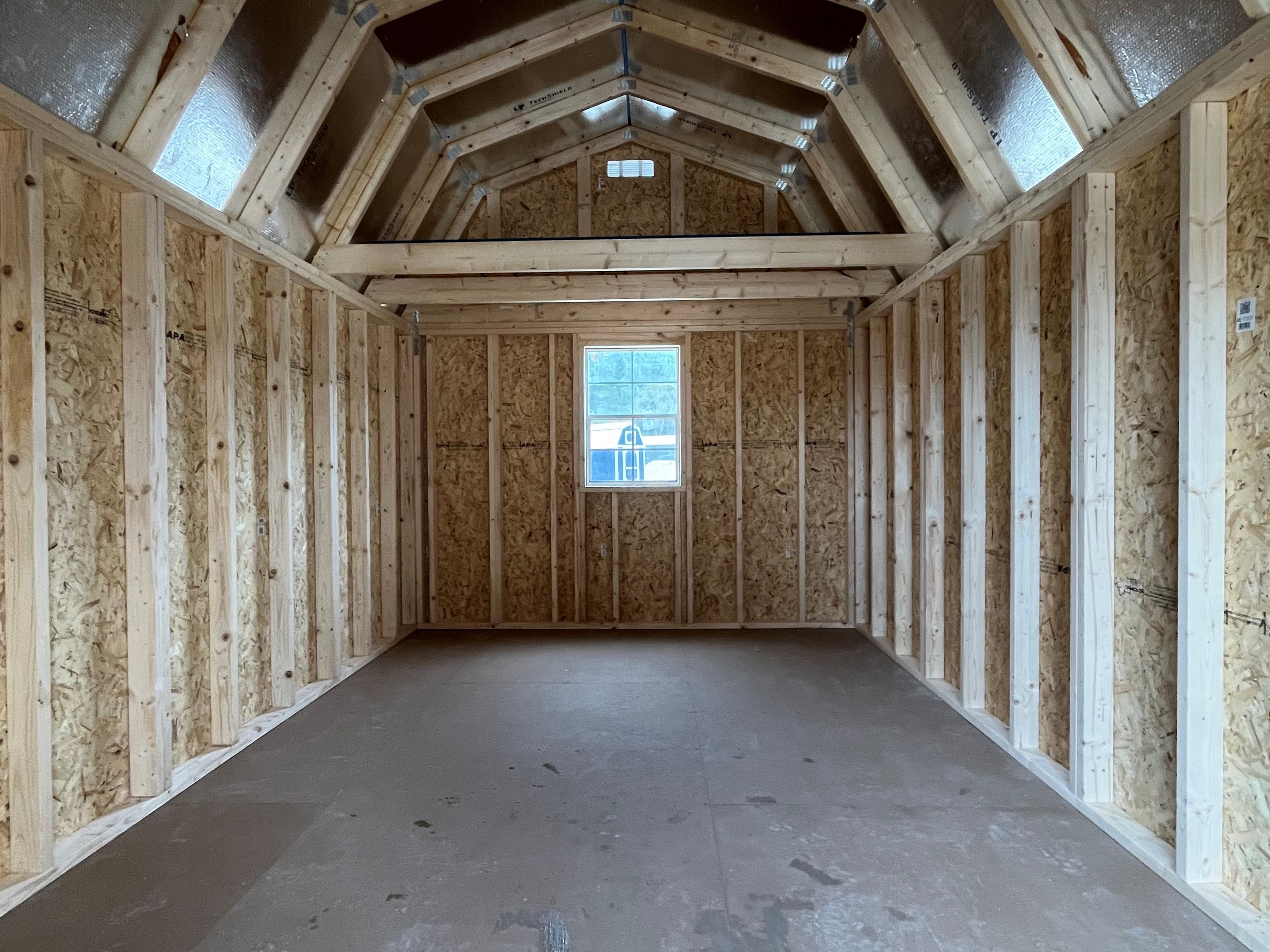 Interior of a lofted barn showing the window on the back wall and eight foot loft in back