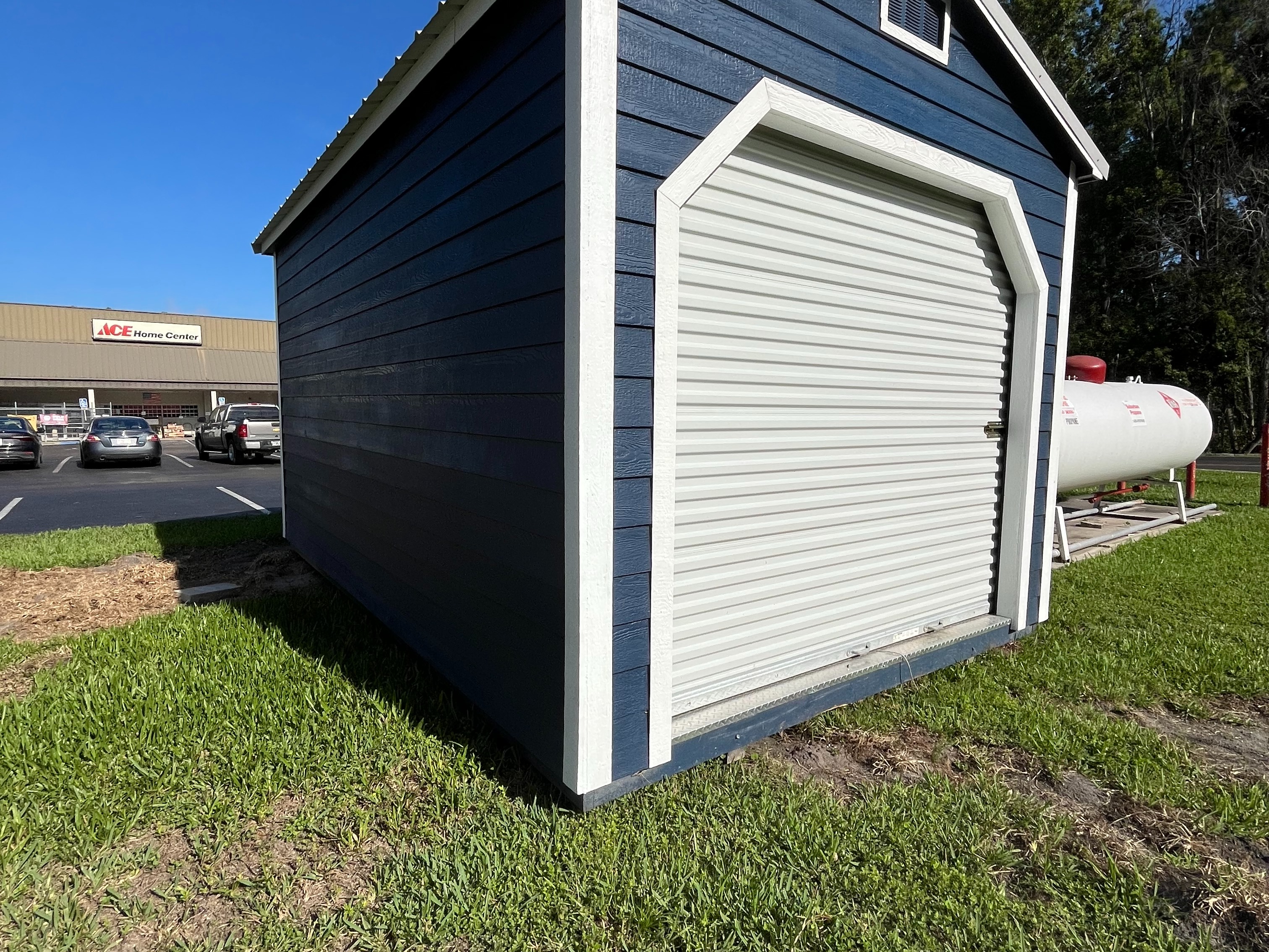 Exterior of a dark blue 10x16 workshop shed showing the lap siding and garage door