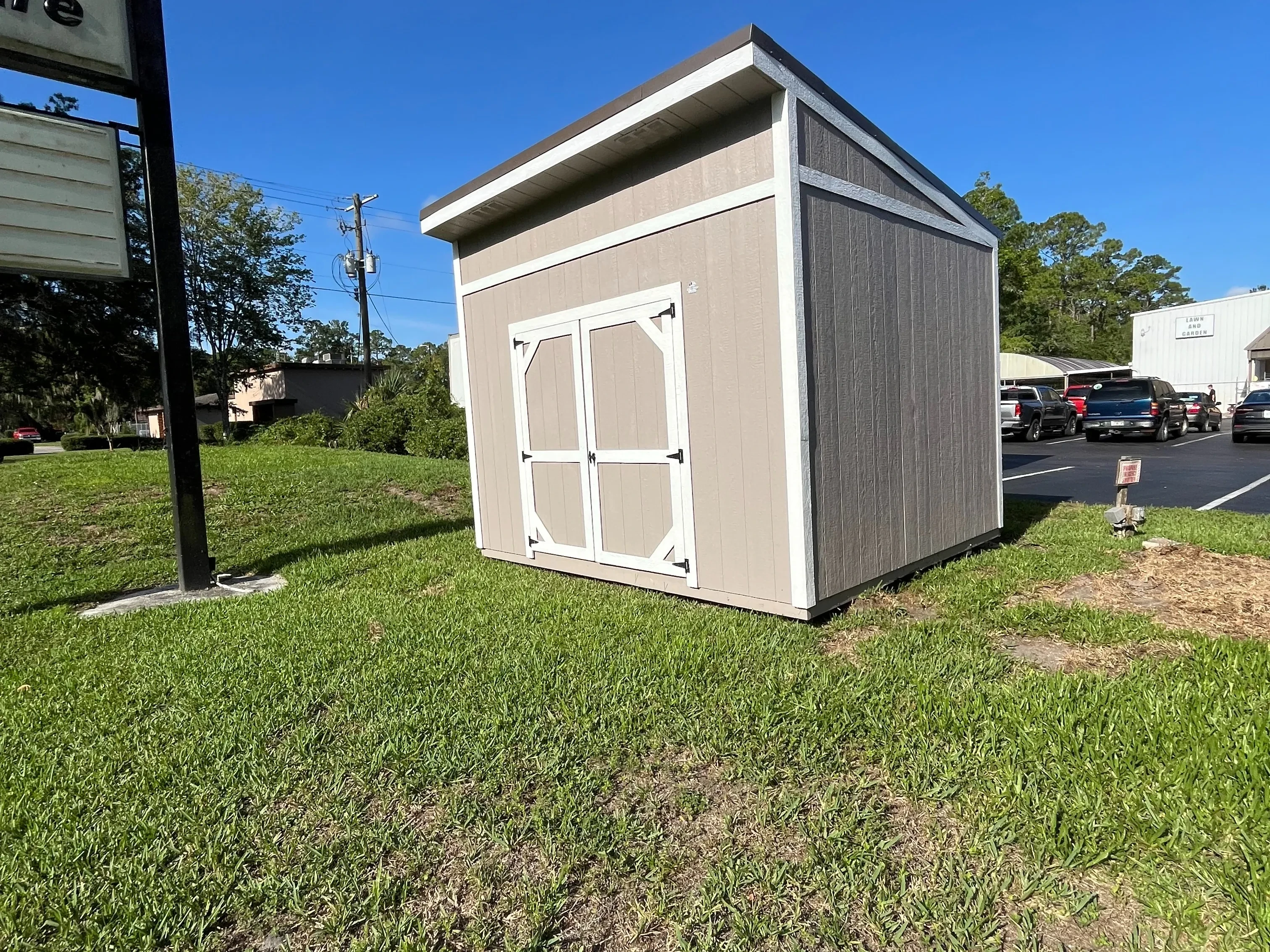 Exterior of a taupe with white trim 10x12 urban shed that has a double wood door