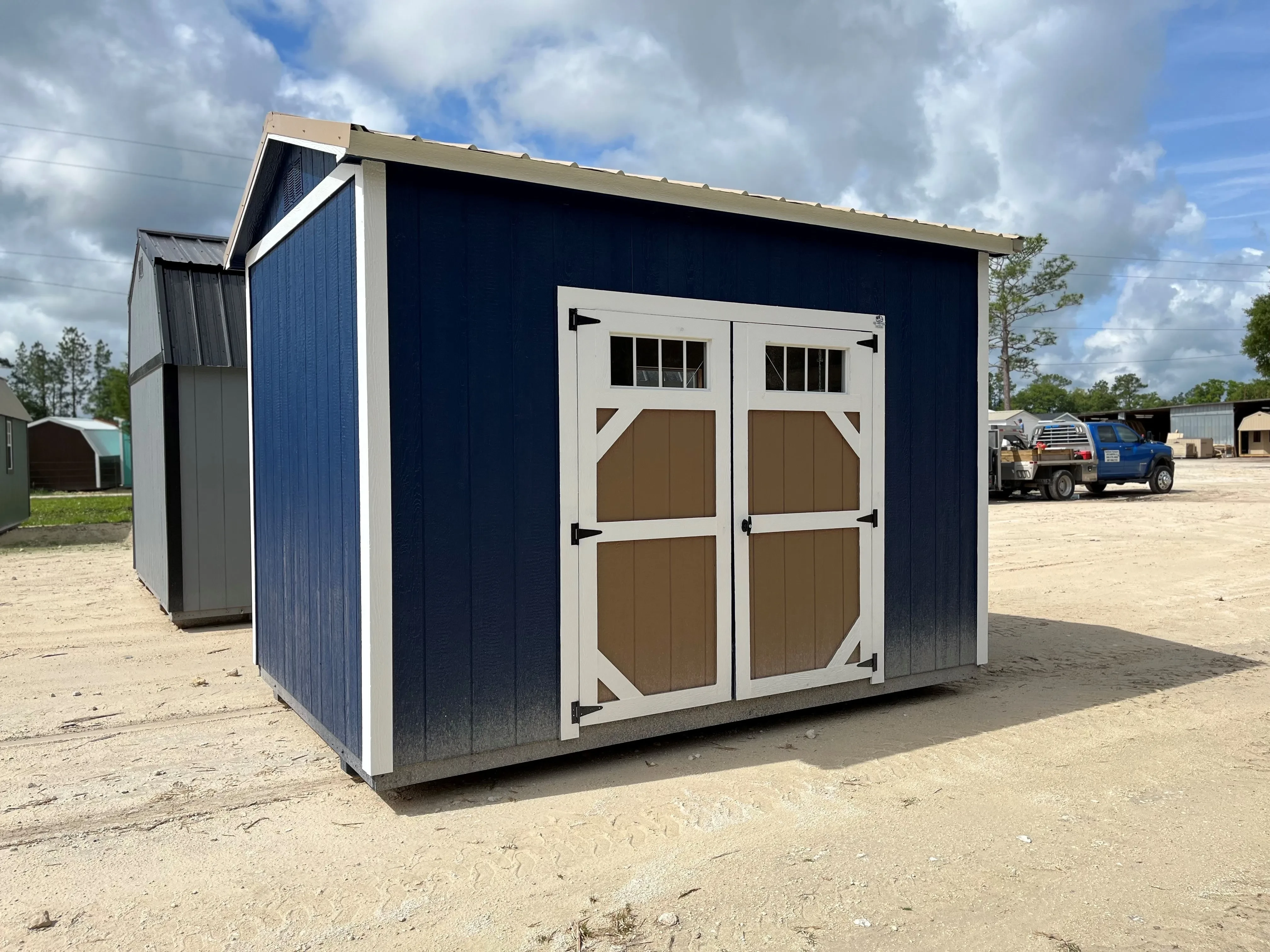 Exterior of an 8x12 side garden shed painted dark blue with a double wood door with windows