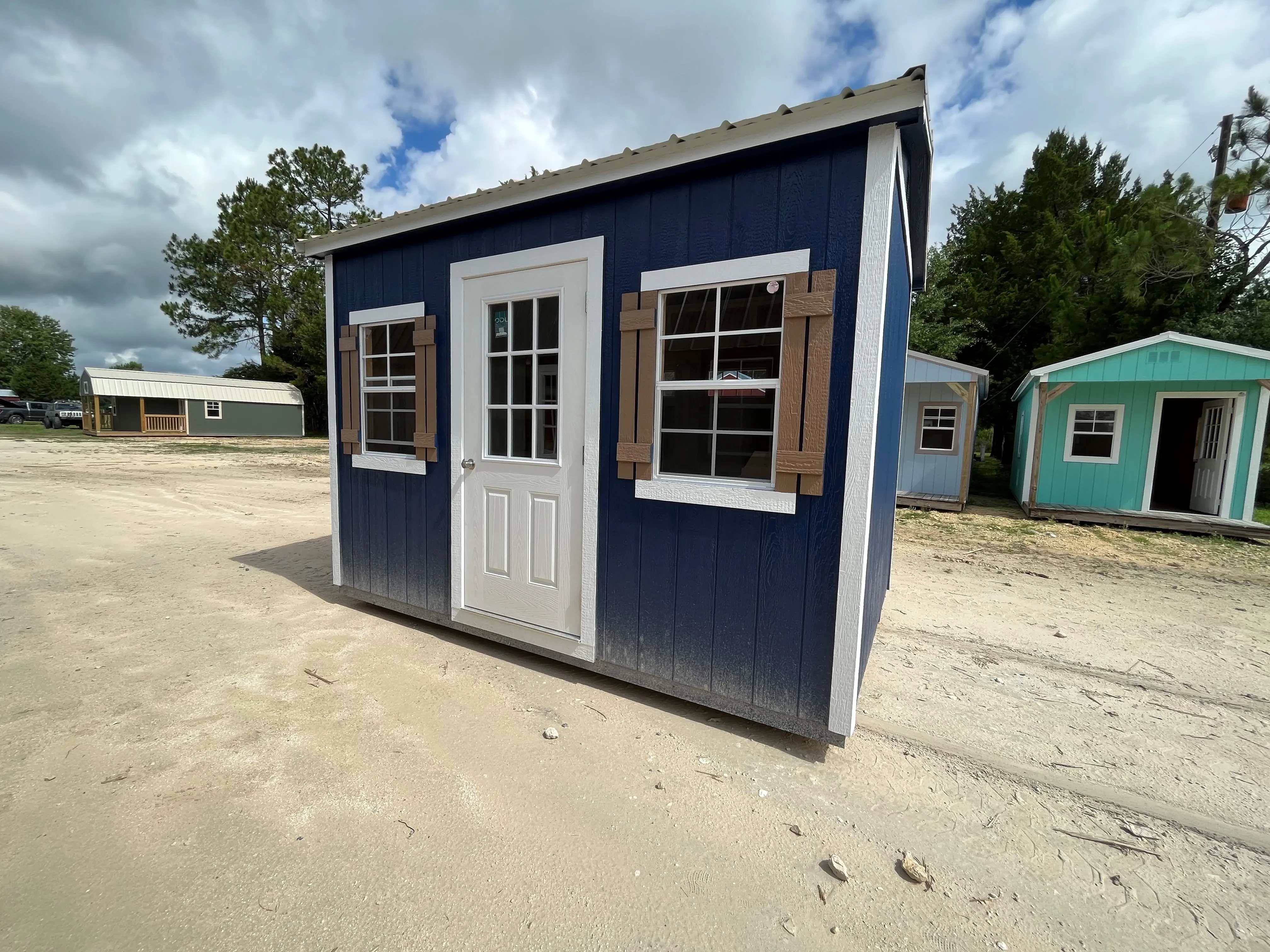Exterior of an 8x12 side garden shed dark blue in color with a walk-in door, windows and shutters
