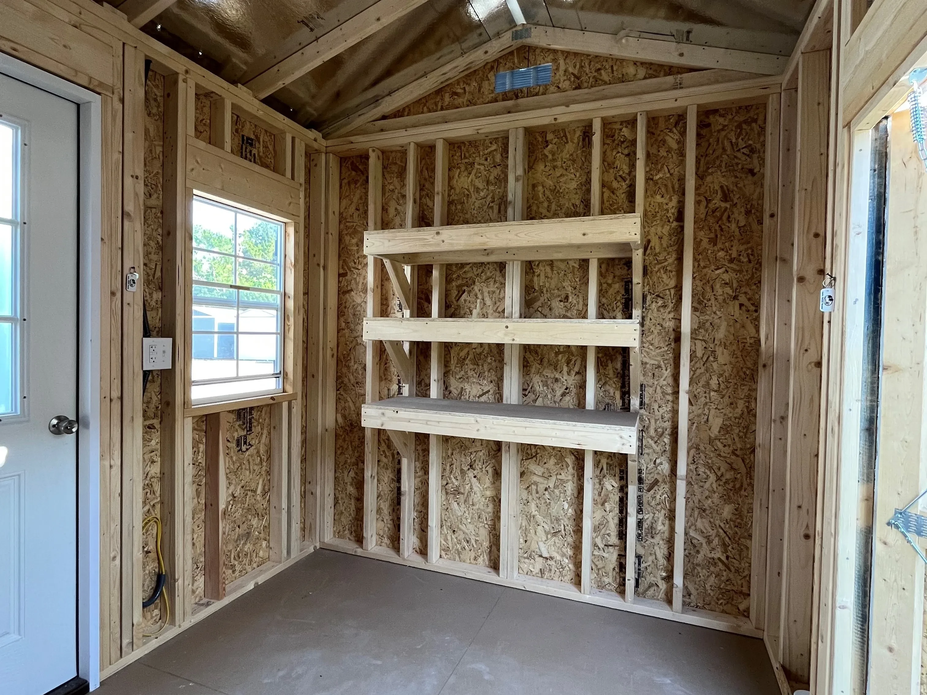 Interior photo of an 8x12 side garden shed showing the walk-in door, window and shelves