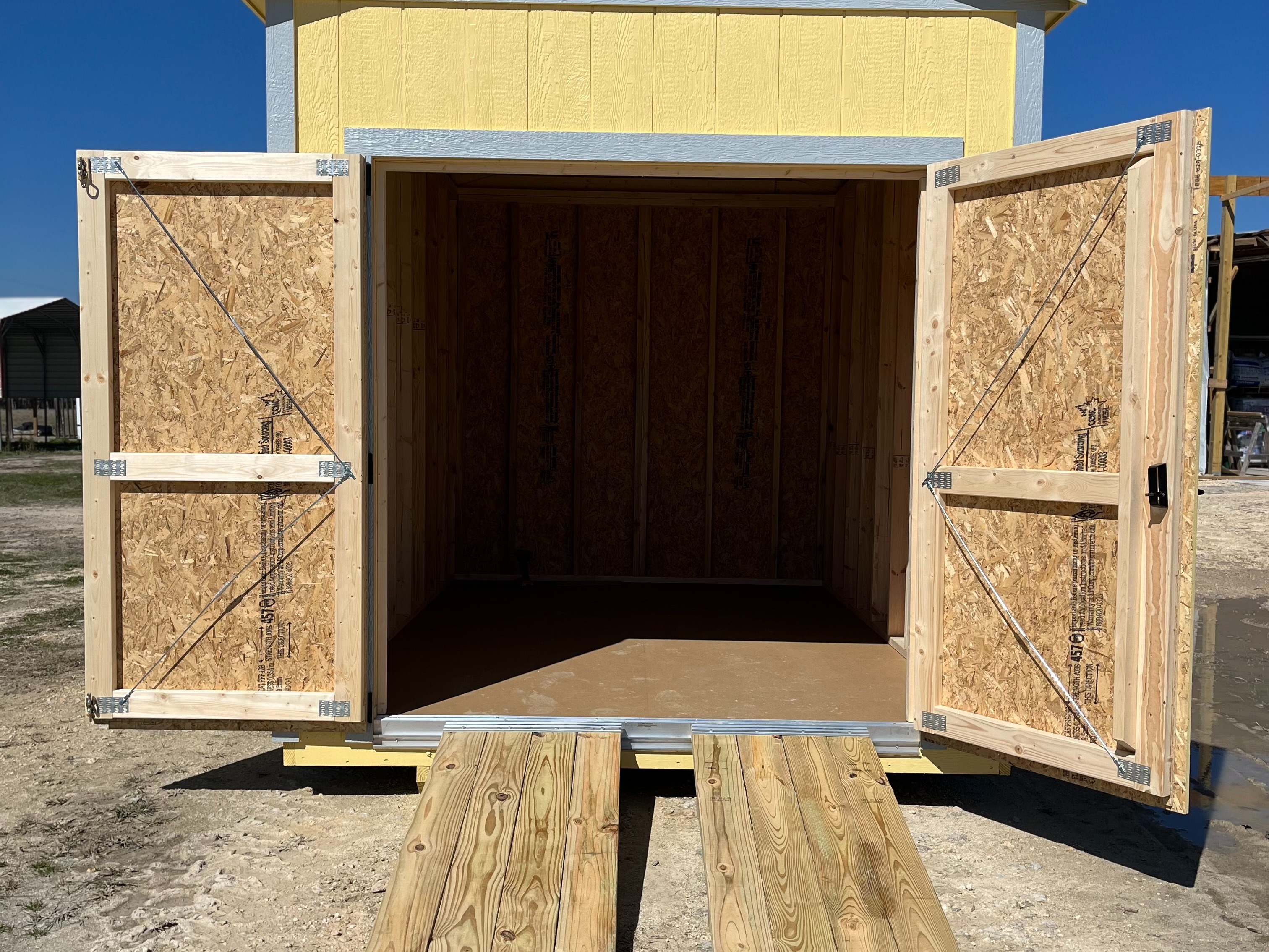 Exterior of an 8x12 garden shed showing both doors open and ramps