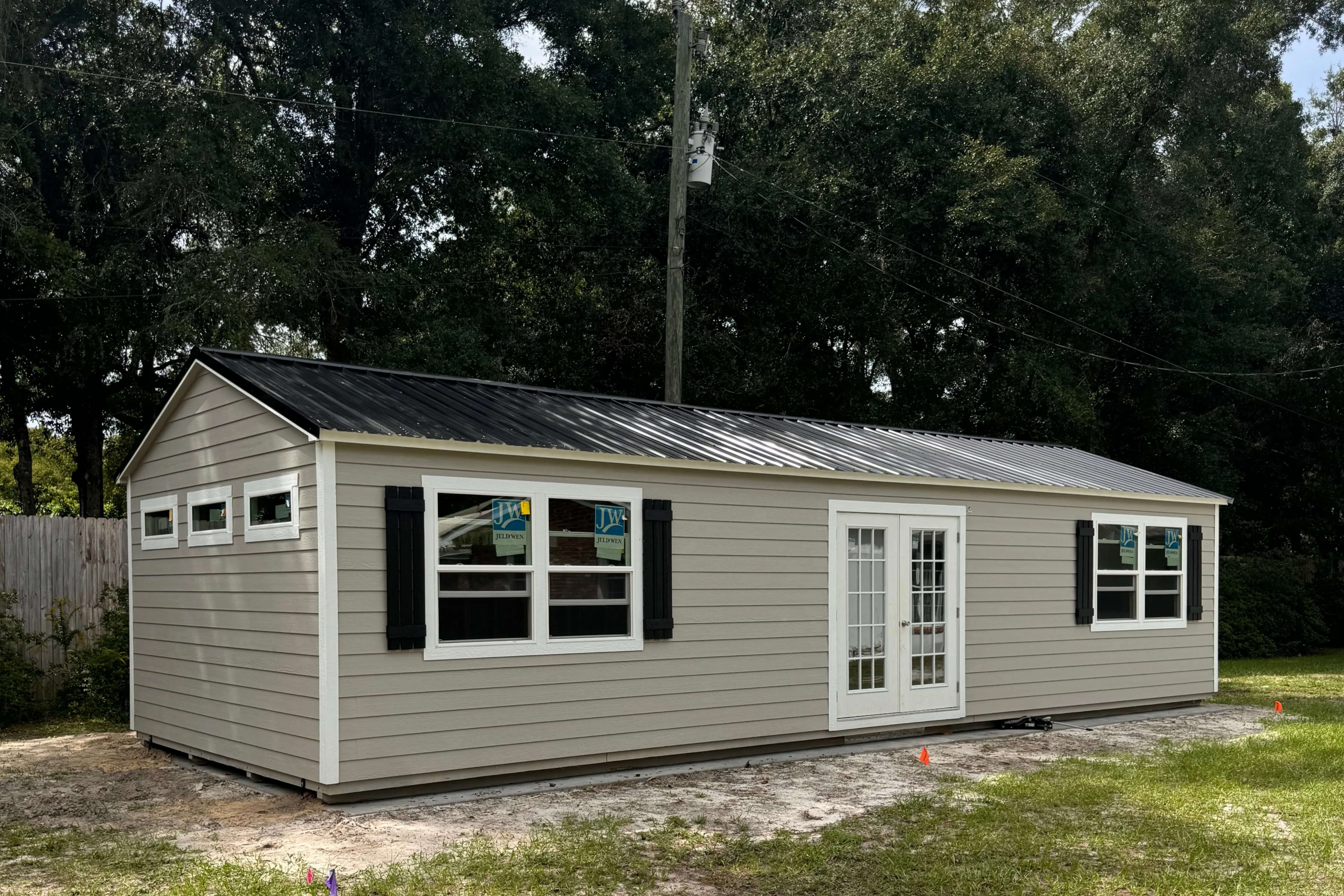 Big lap siding shed with patio doors, double windows, and transom windows