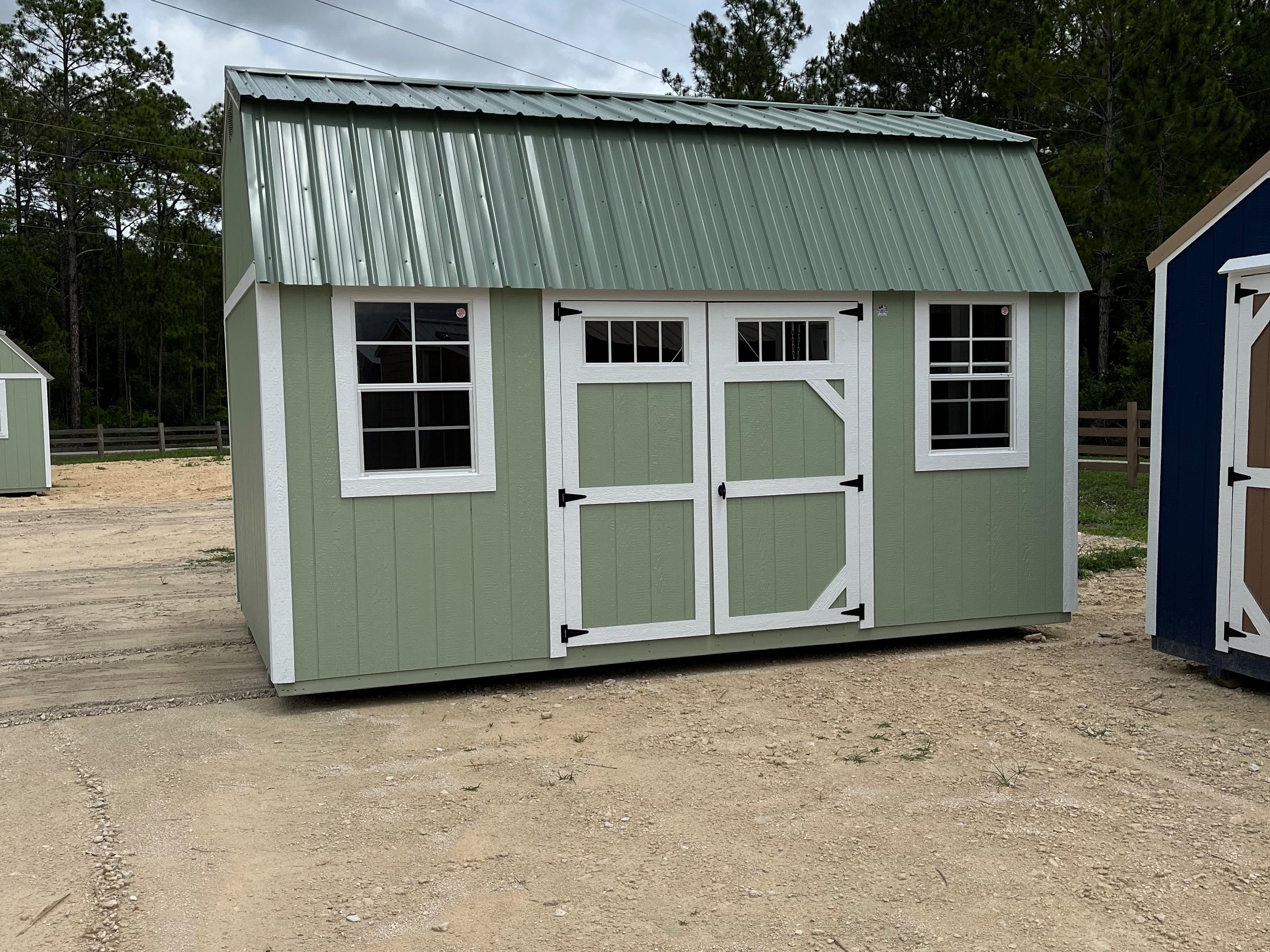 Exterior of a 10x16 side lofted barn with a double wood door with transom and windows