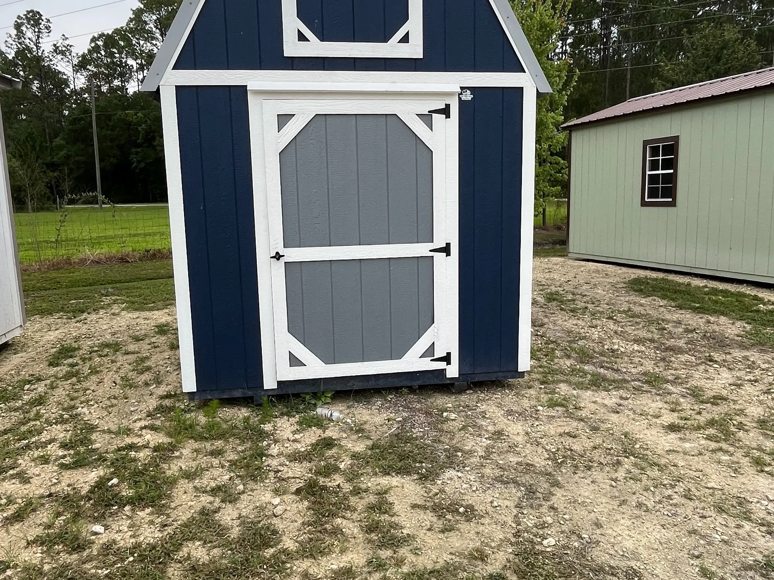 Exterior of the dark blue 8x12 lofted barn viewing the grey door