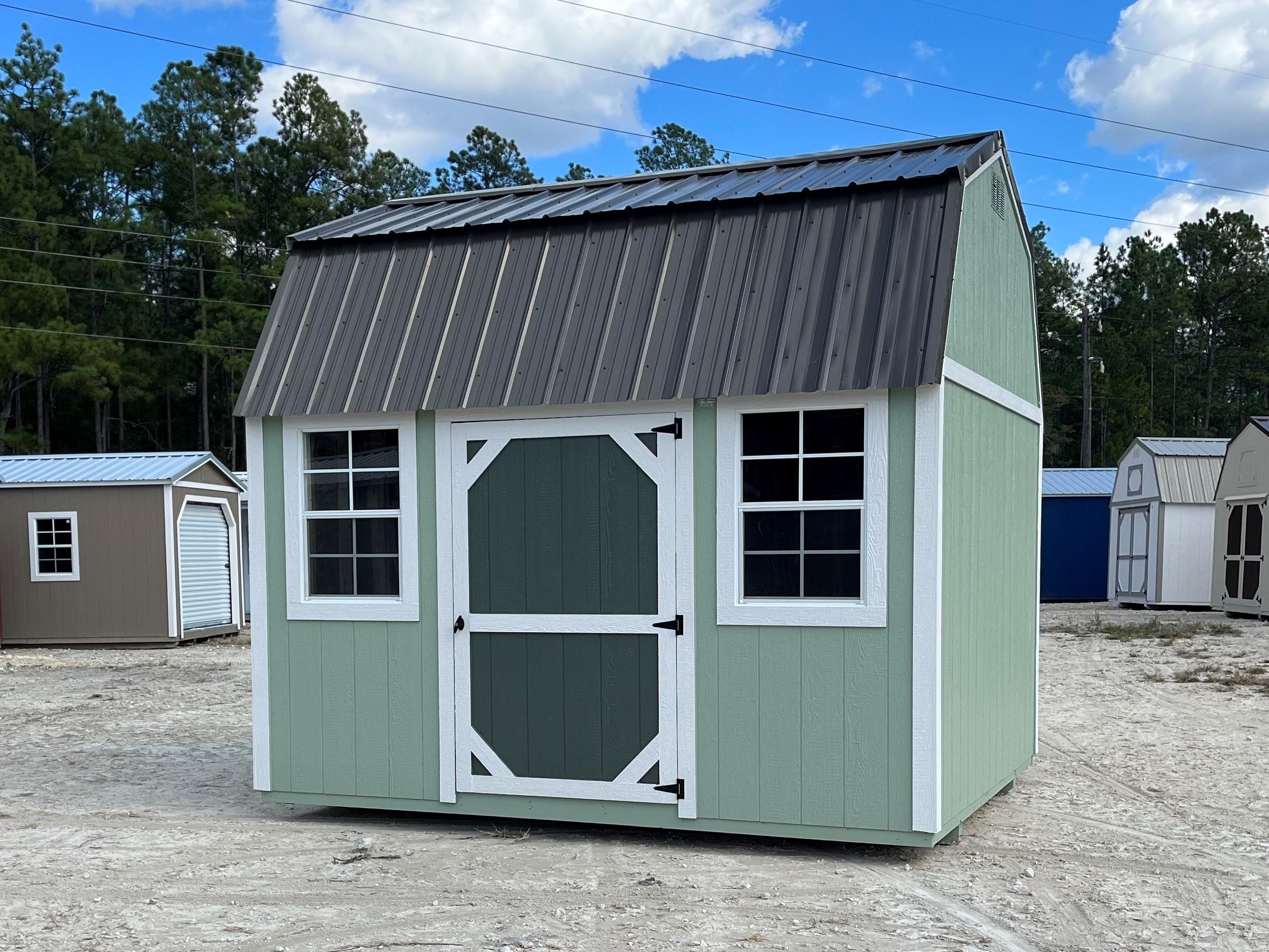 Exterior of a sage green 10x12 side lofted barn with a single wood door and windows