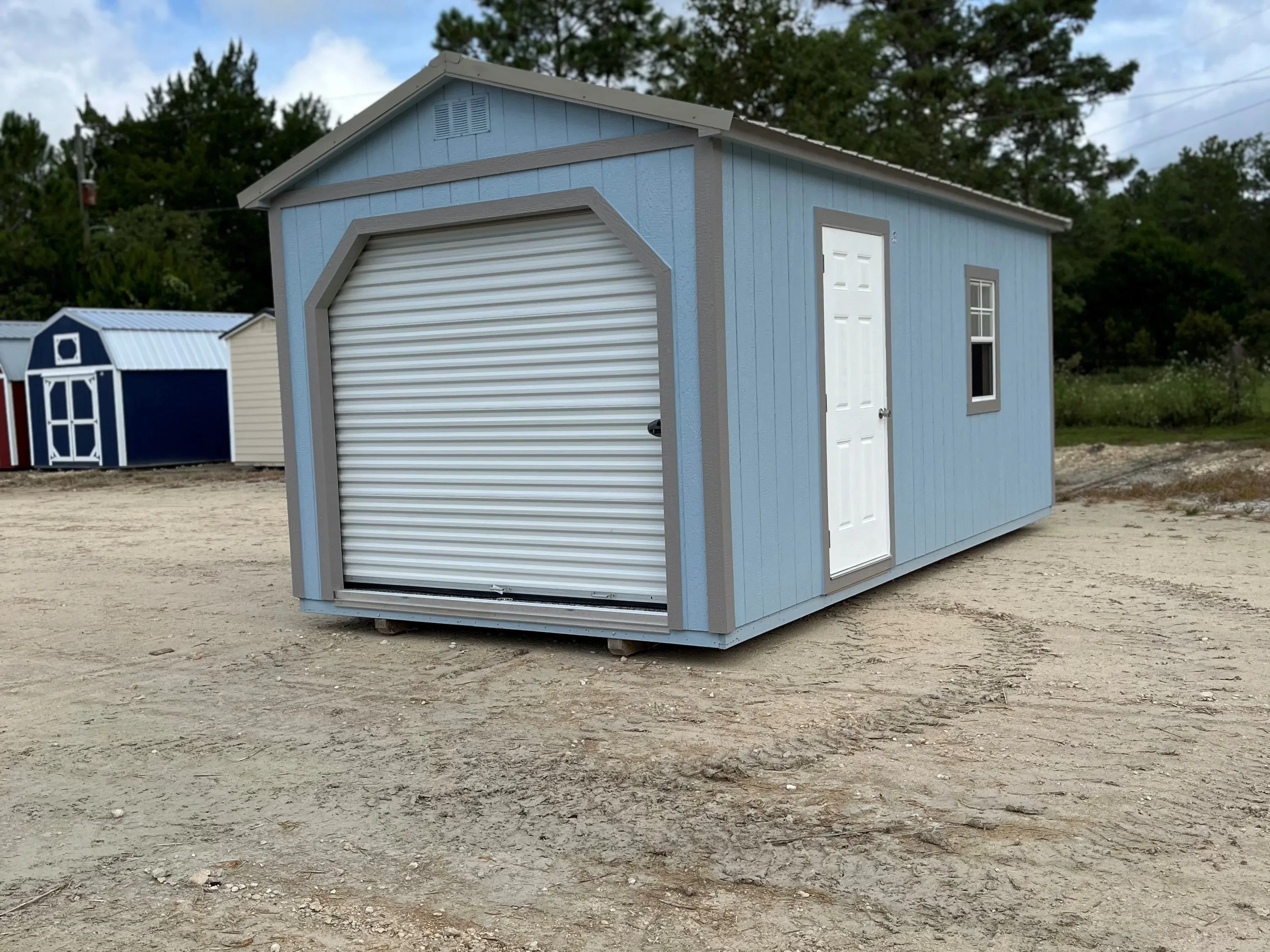 Outside of a 10x20 workshop with an entry door and one window on the side wall and a roll up door on front the shed