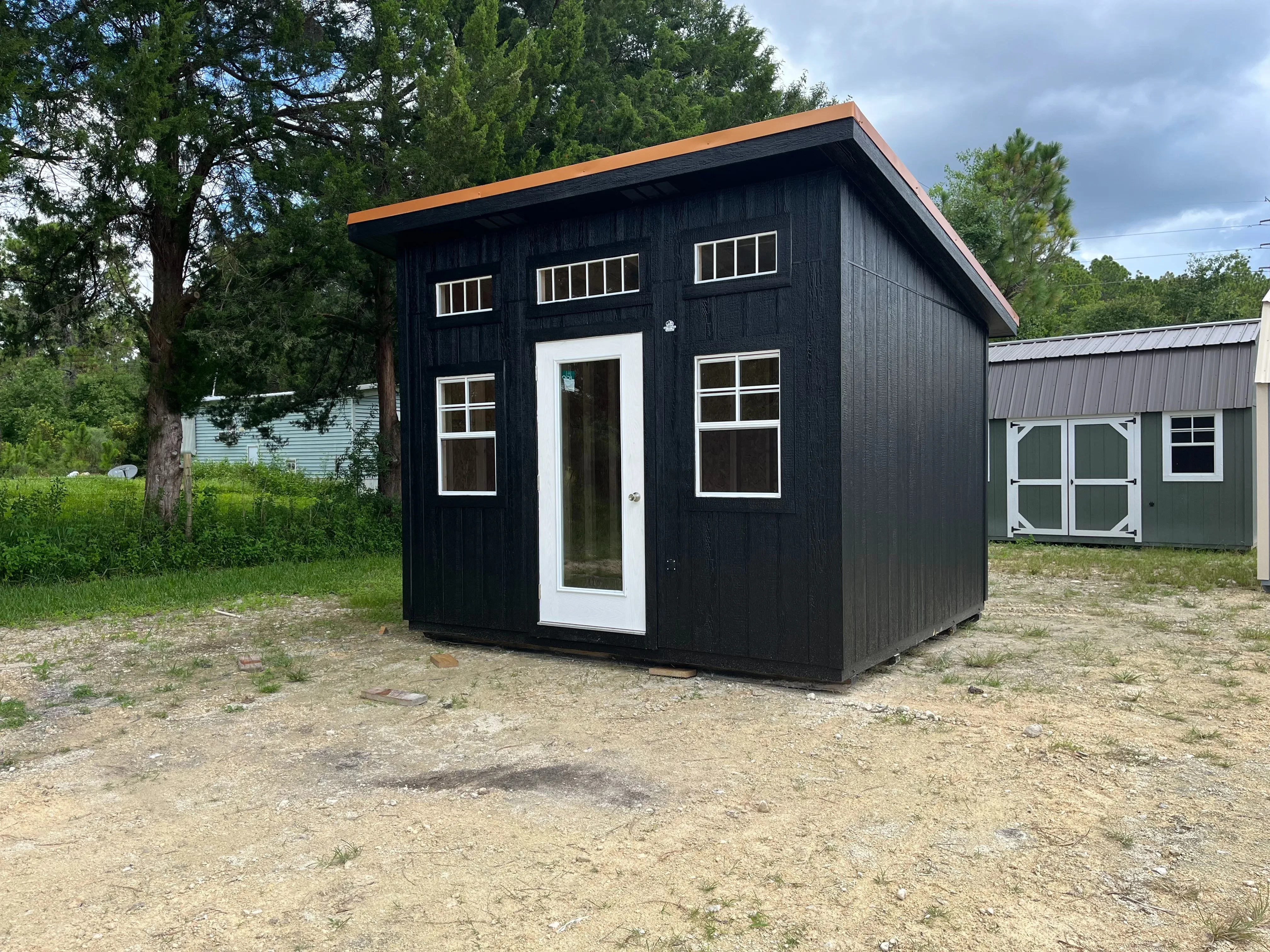 Front of black 12x12 urban shed with single full lite entry door and many windows