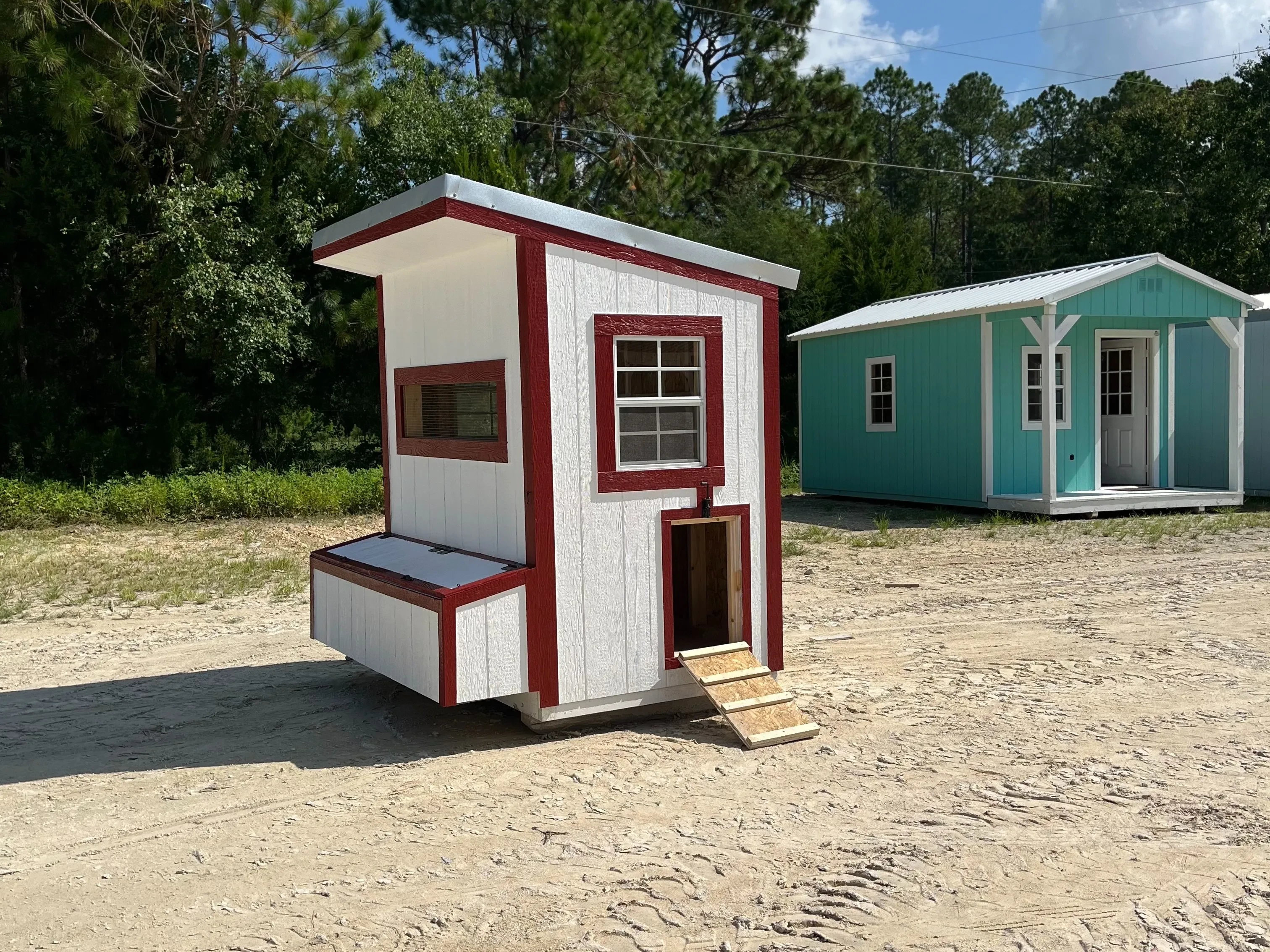 Exterior of a white and red 4x6 chicken coop with a window, layer boxes and chicken access ramp