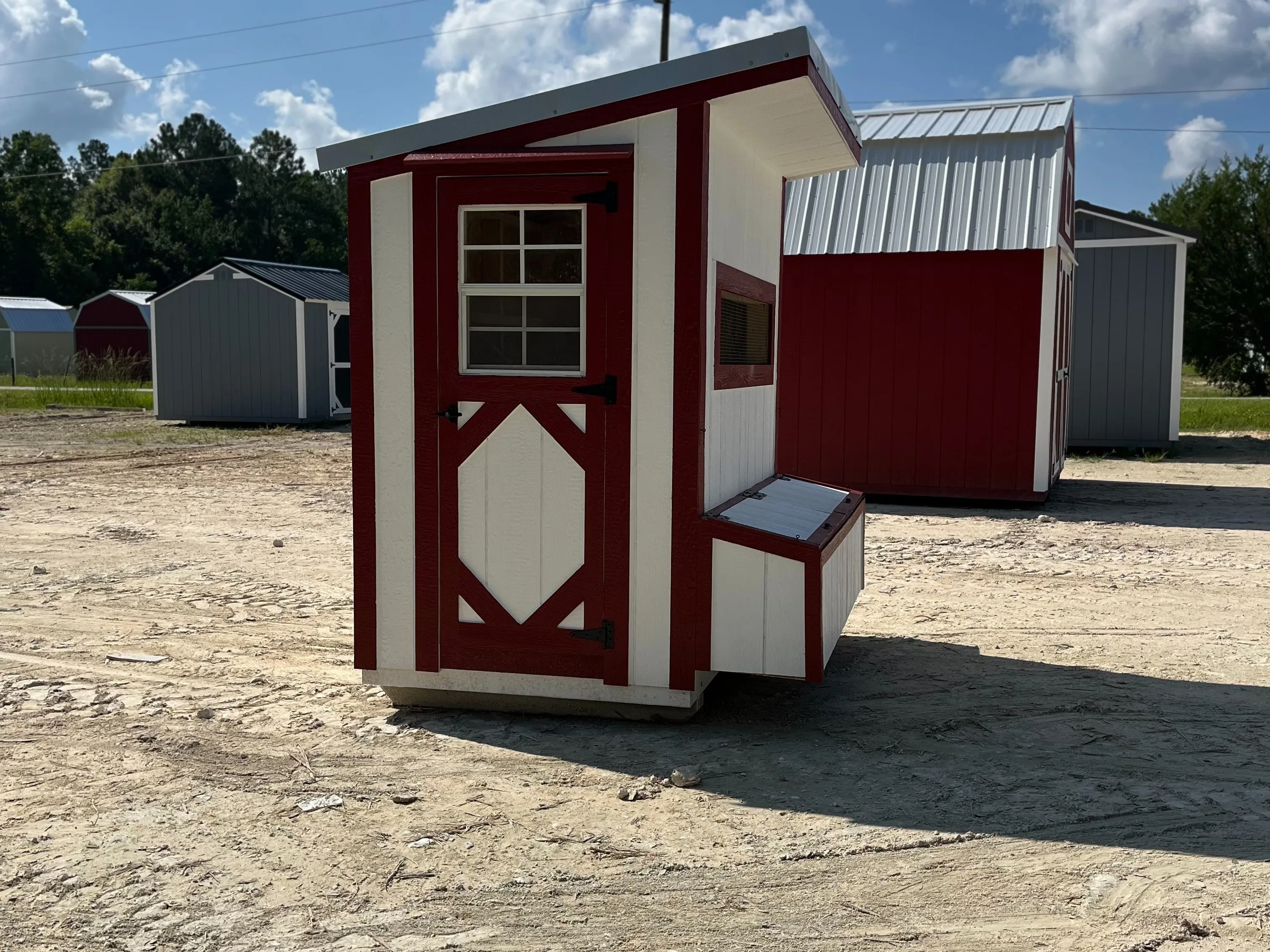 Exterior of a white and red 4x6 chicken coop with a window, layer boxes and single wood door