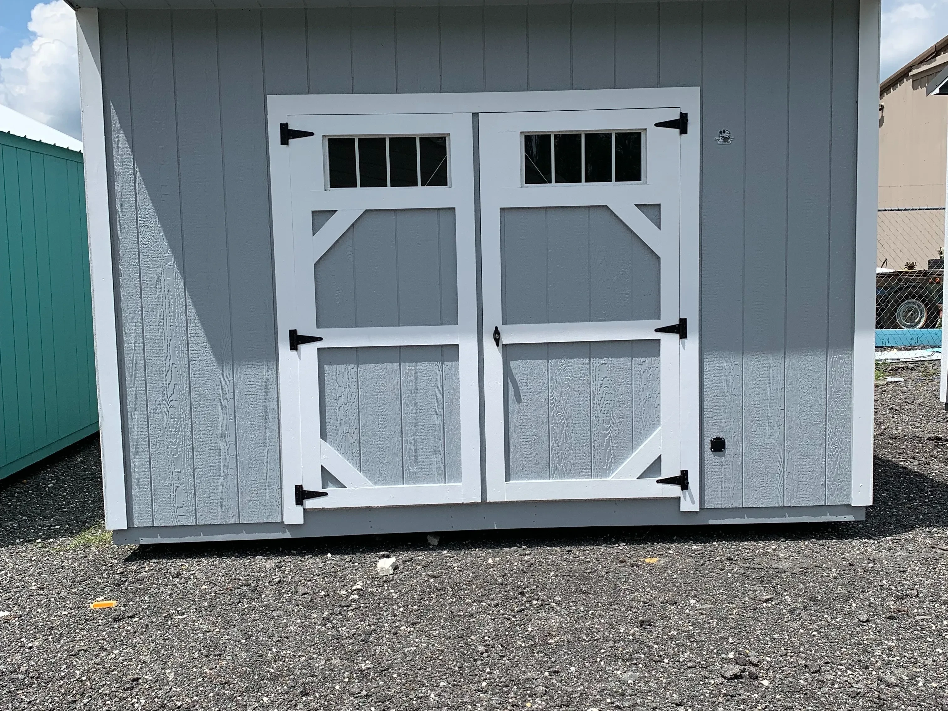 Exterior of a light grey 10x12 urban with double wood doors and transom window