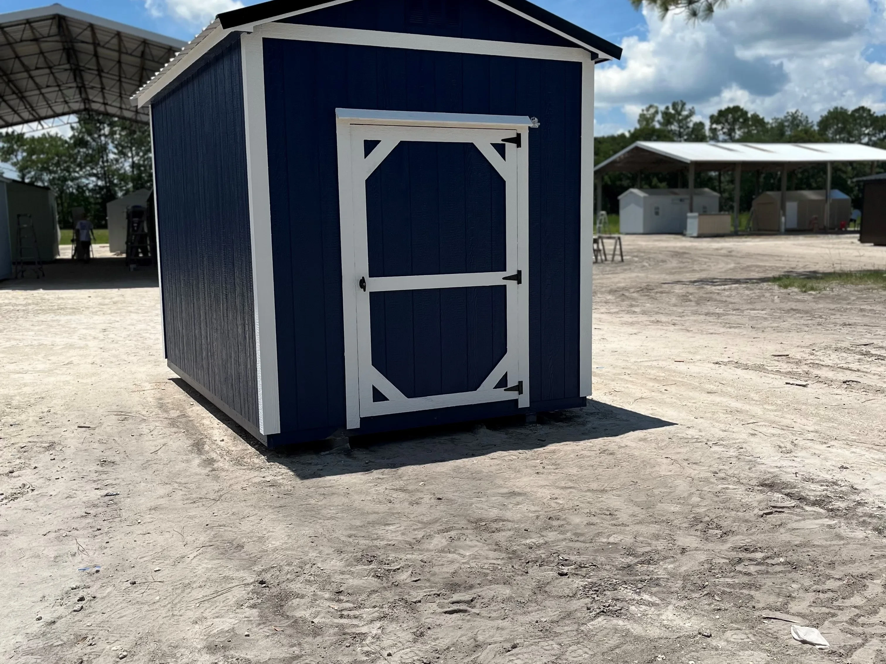 Outside of an 8x12 garden shed, painted dark blue with white trim and a black metal roof