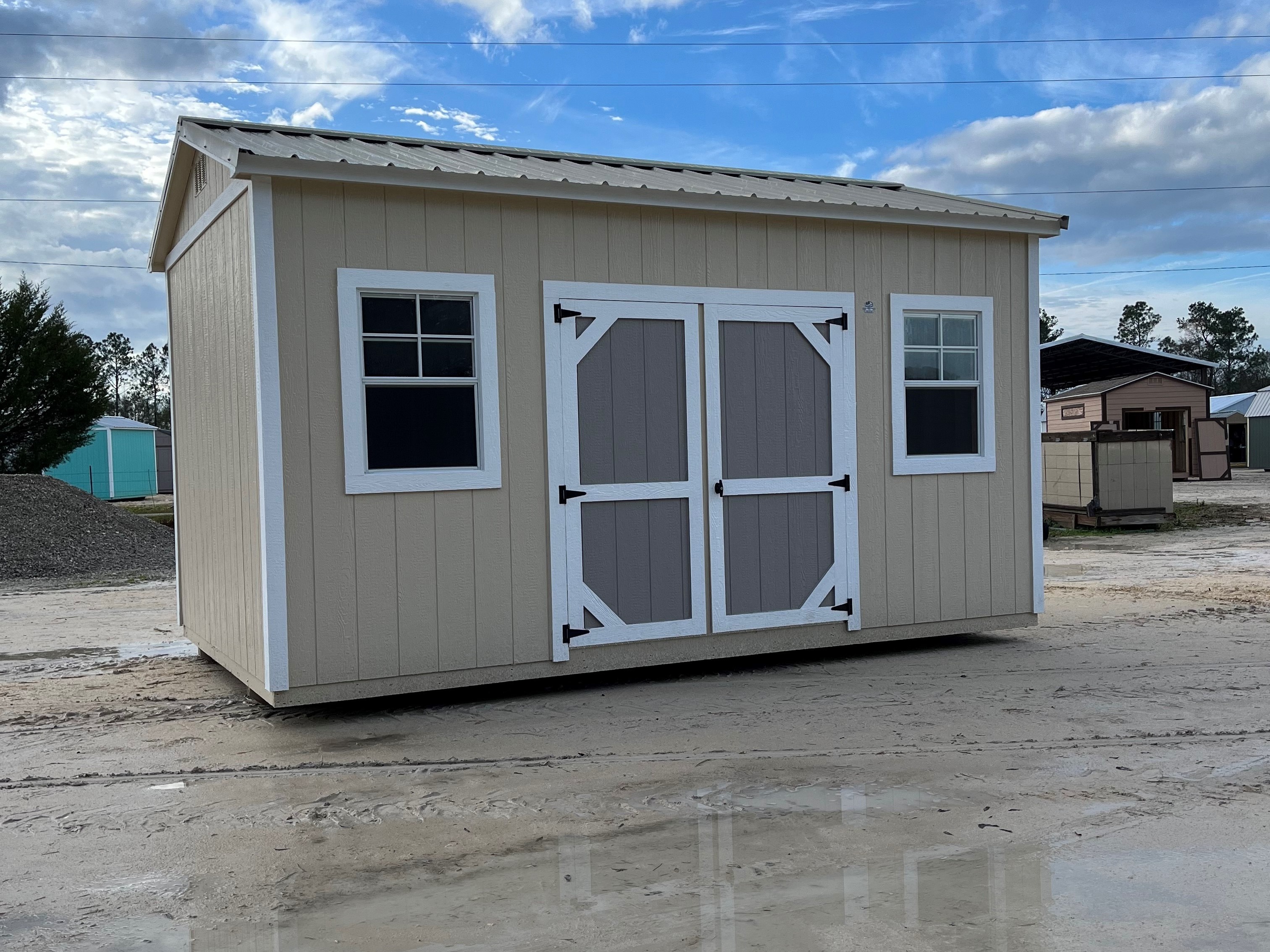 Outside of a 10x16 side garden shed with double wood doors and two windows on the side, and a metal roof