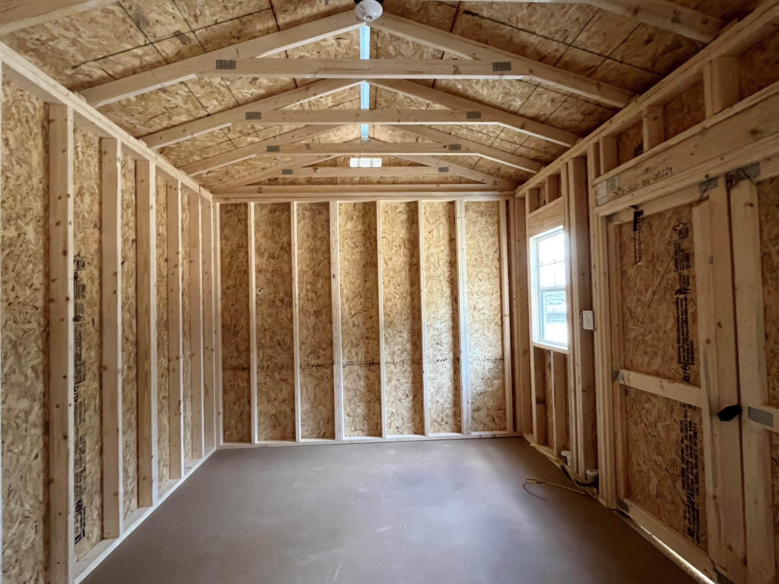 Interior of a 10x16 side garden shed showing the inside of the double wood doors and a window