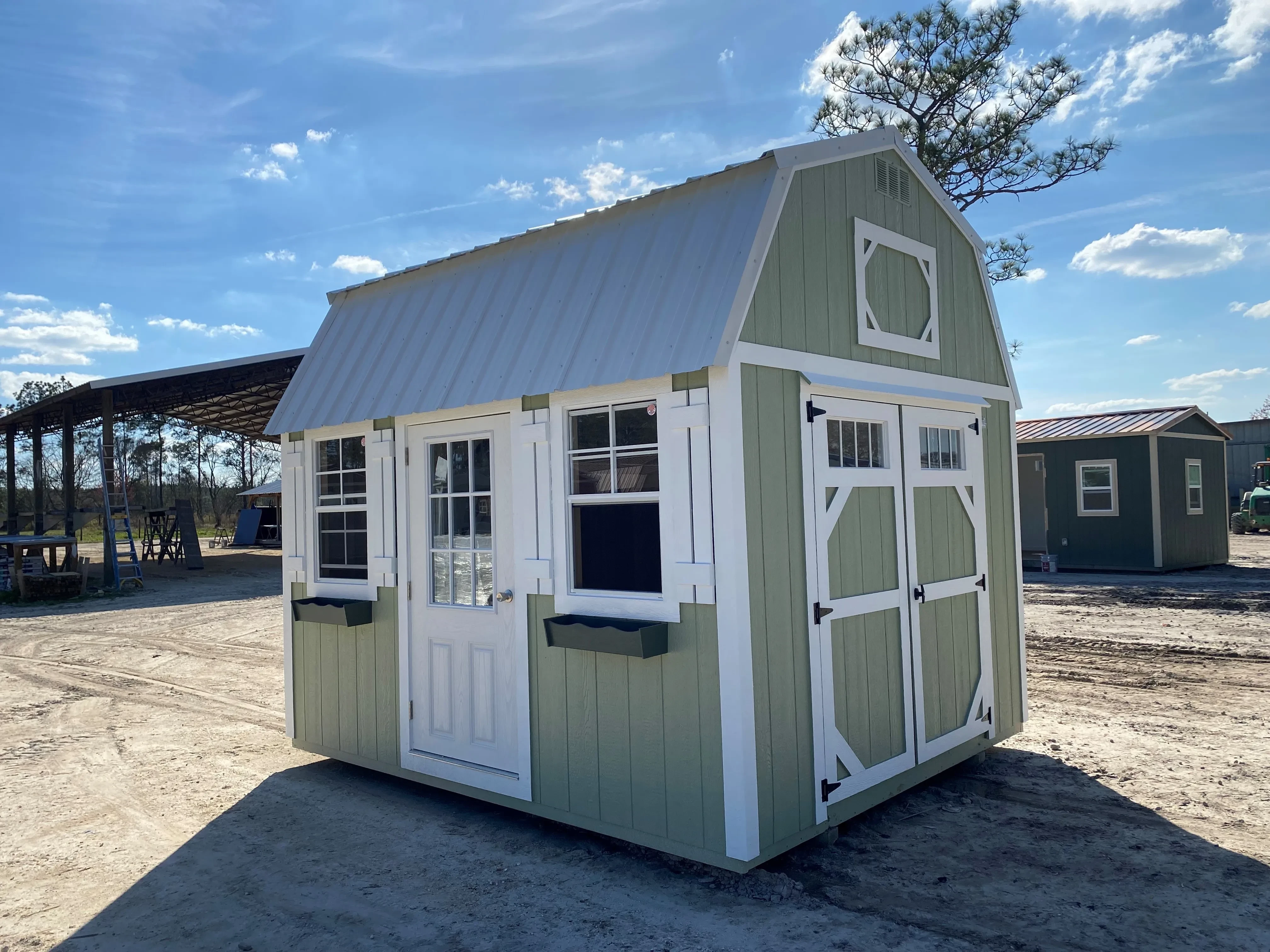 Outside of 10x12 side lofted barn with many windows, a single entry door, and double wood door with transom on the end