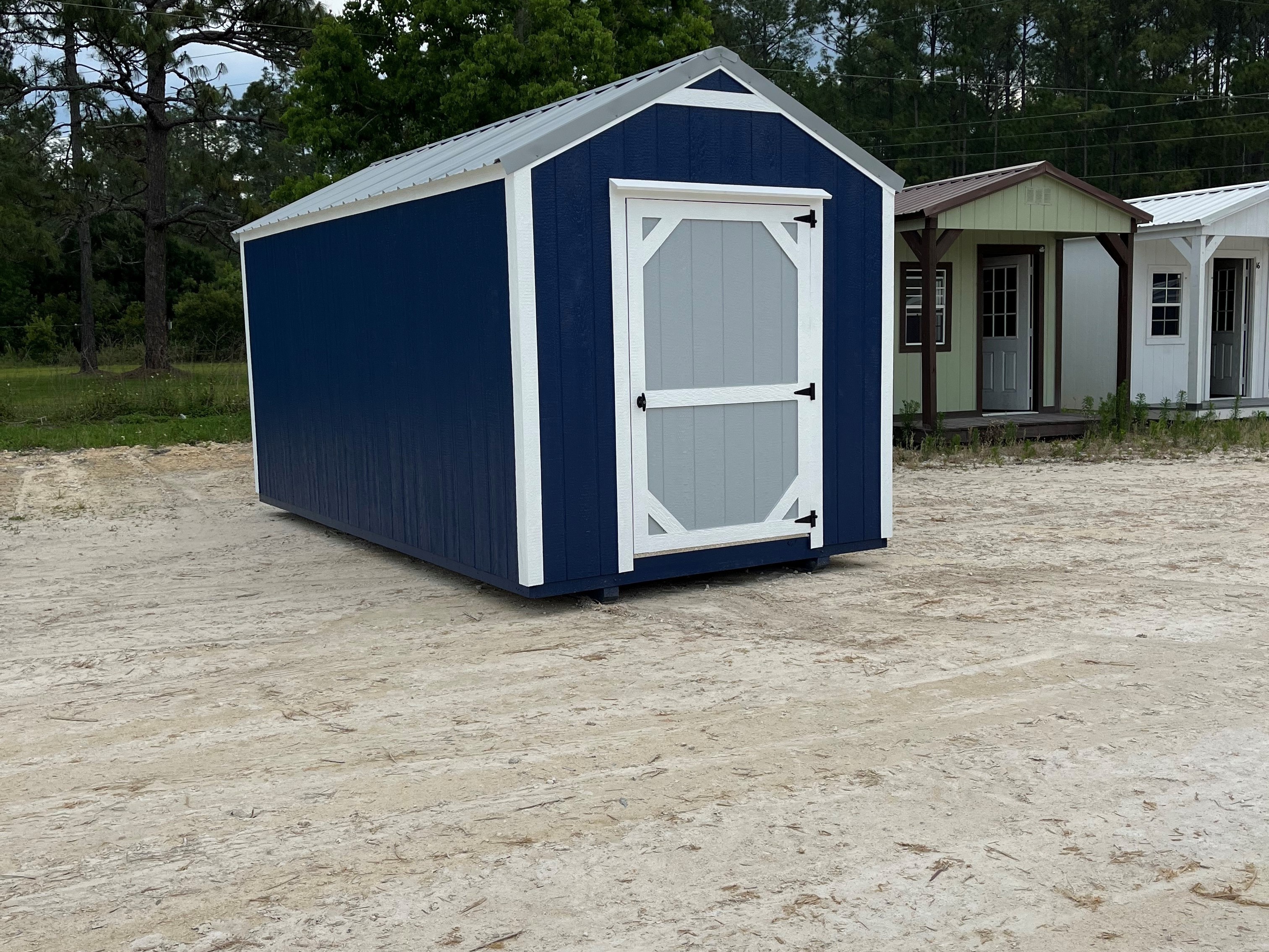 Outside of a blue 8x16 garden shed economy with a grey door and metal roof