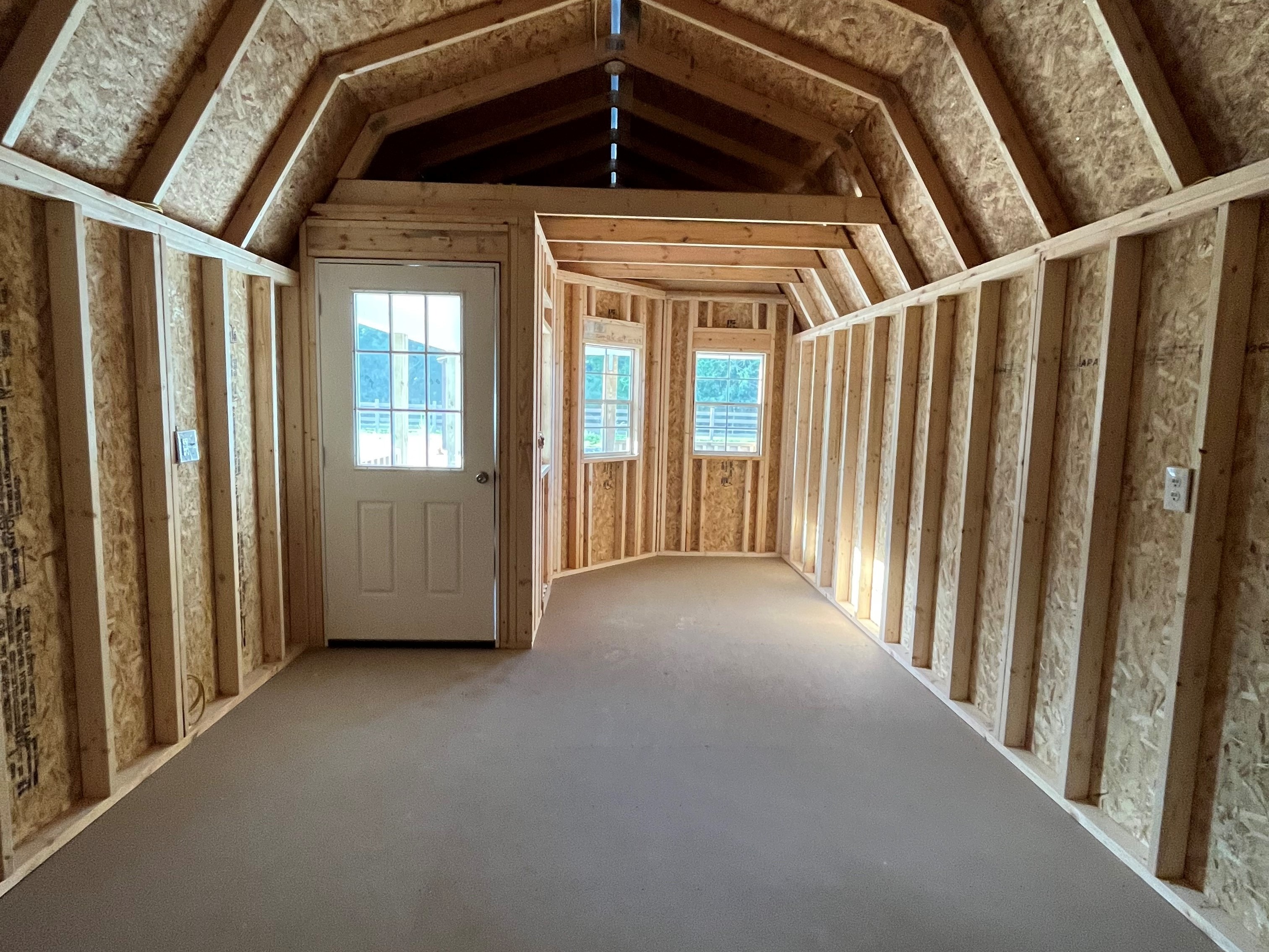 Interior of a 12x32 deluxe lofted barn cabin showing a loft in the front, the entry door and windows