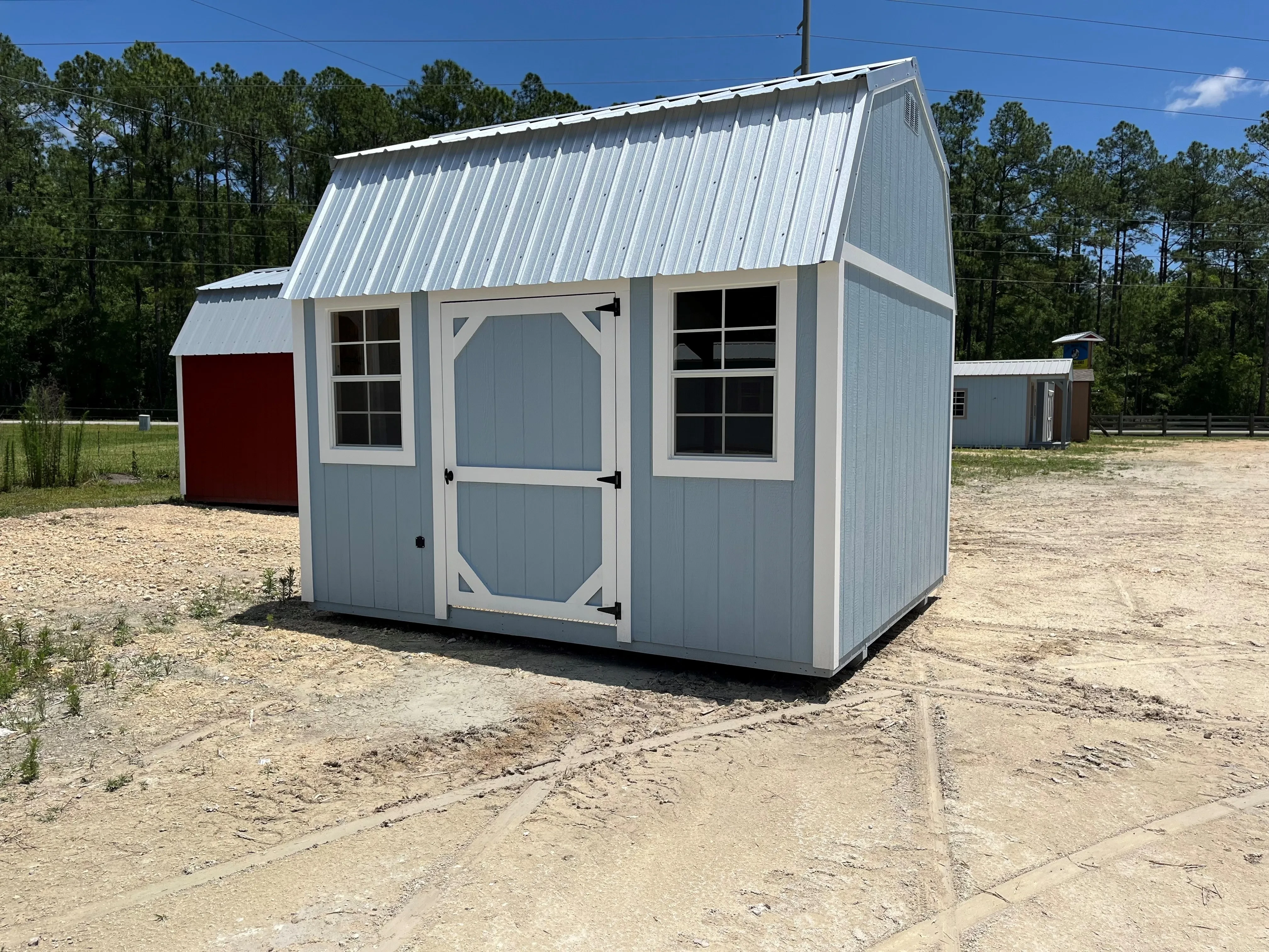 Exterior a light grey side lofted barn with a single wood door and windows