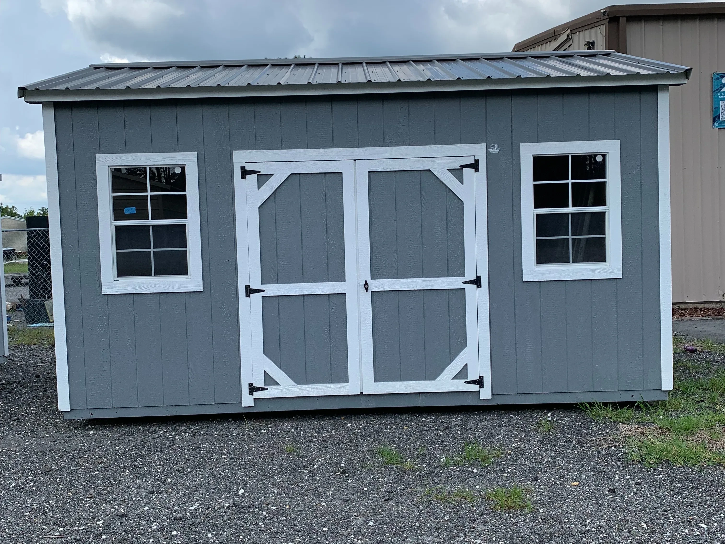 Exterior of a dark grey 10x16 side garden shed with double wood doors and windows