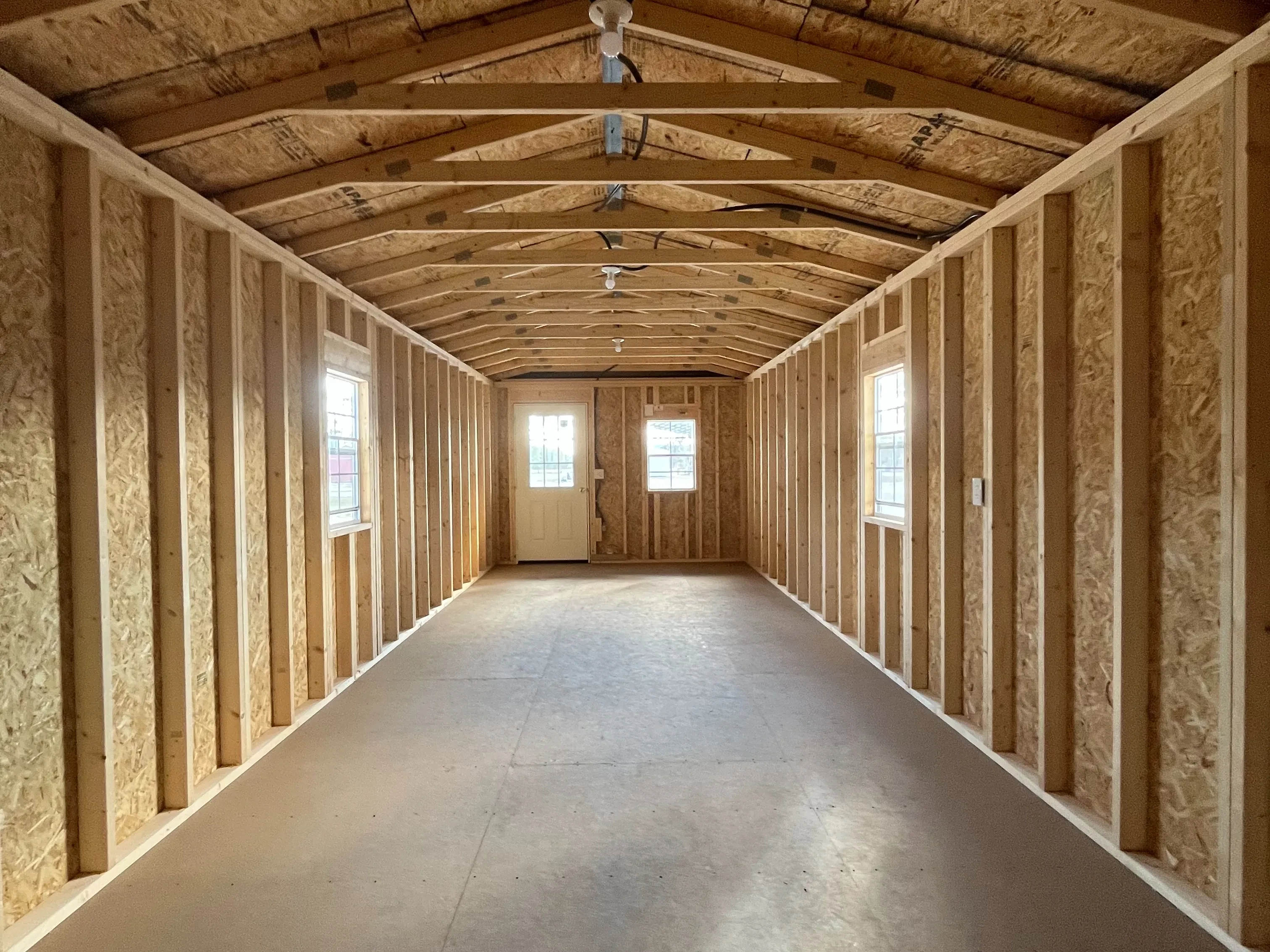 Interior of a 12x36 cabin showing from the back wall featuring windows and walk-in door.