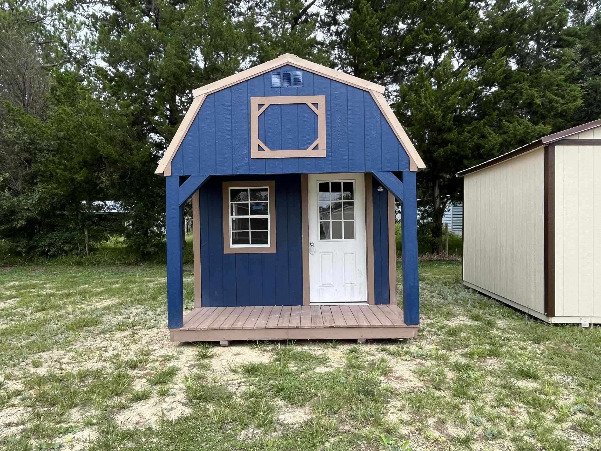 Exterior front of a dark blue 10x24 lofted barn cabin with a porch, walk-in door and window