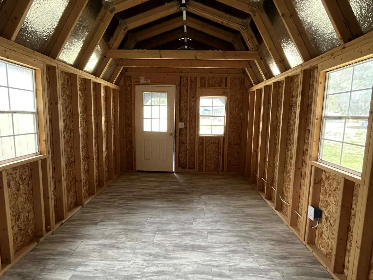 Interior view of a 10x24 lofted barn cabin showing the loft, walk-in door and windows