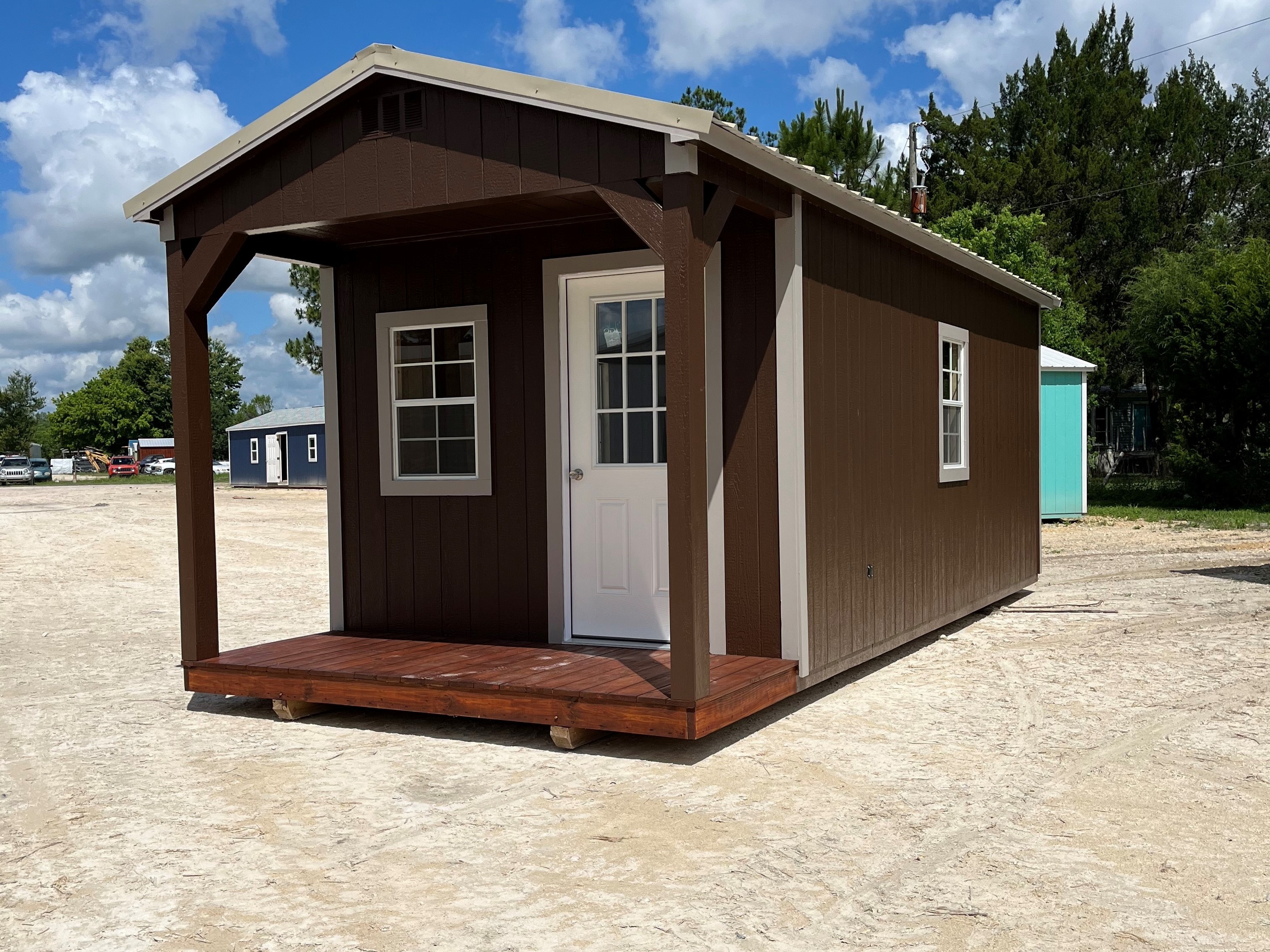 Outside of a brown 10x24 cabin, showing a porch, two windows, and an entry door