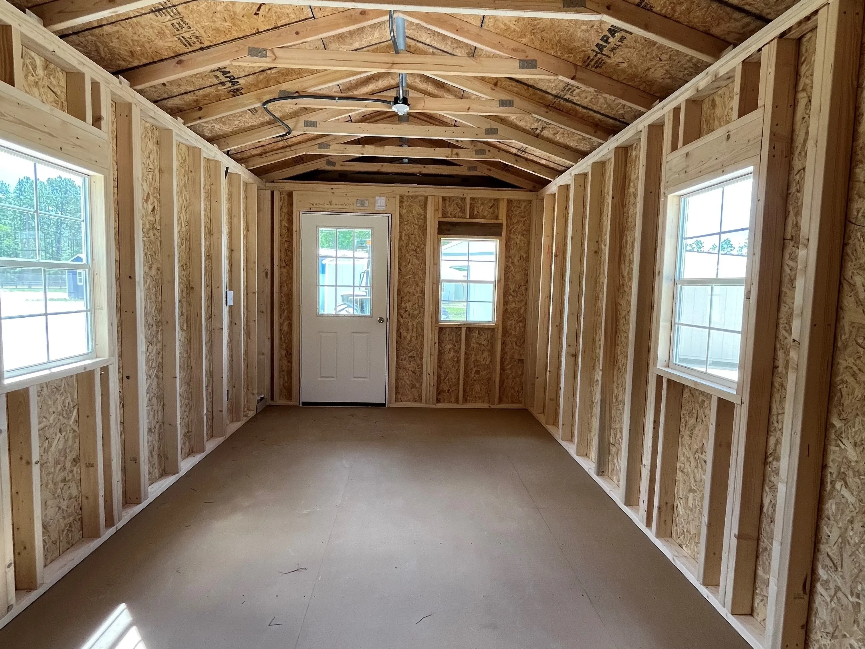 Inside of 10x24 cabin showing three windows, electric, and inside of the entry door.