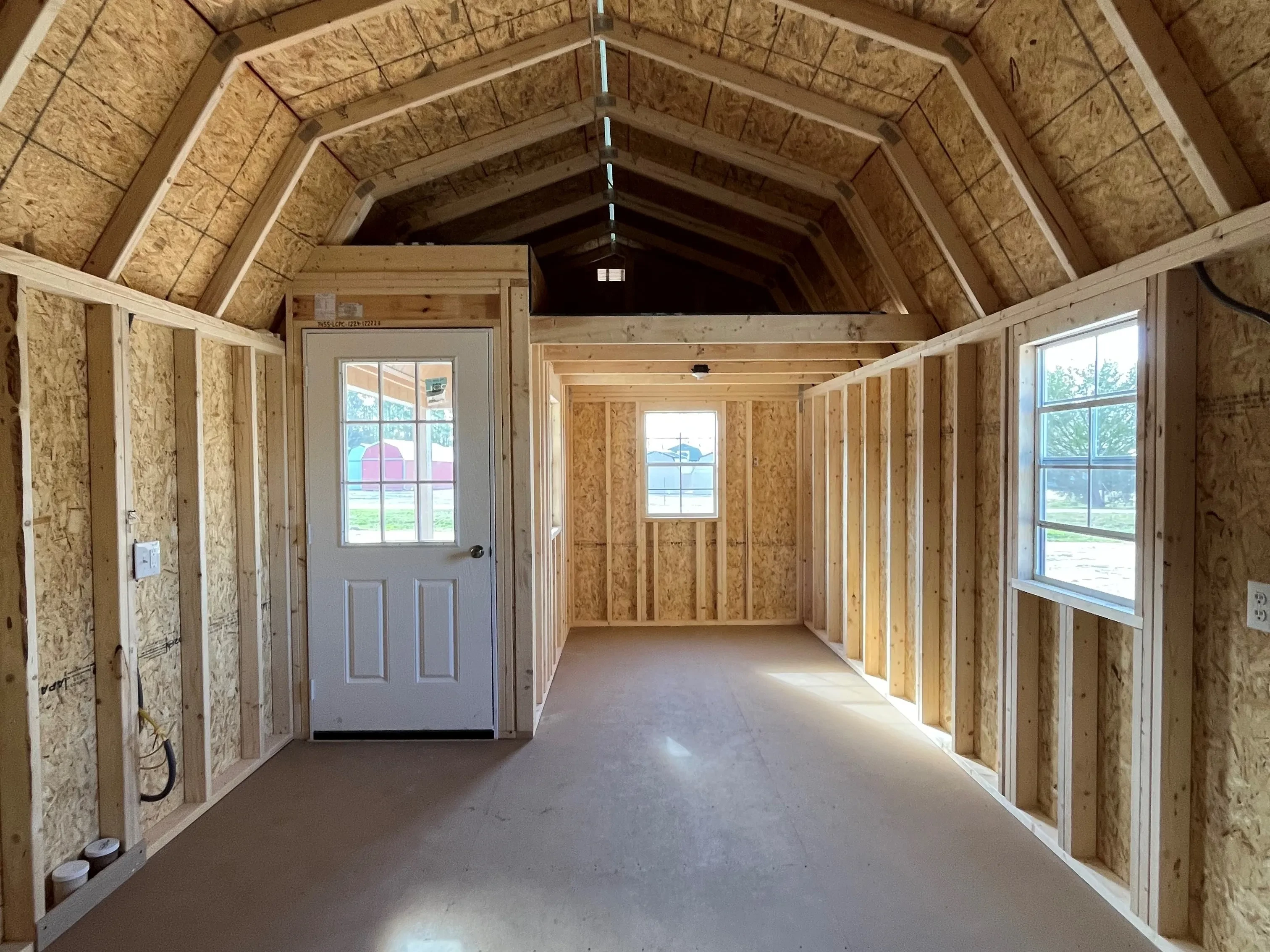 Inside of a 12x24 lofted corner porch cabin showing an entry door, two windows, and a small loft
