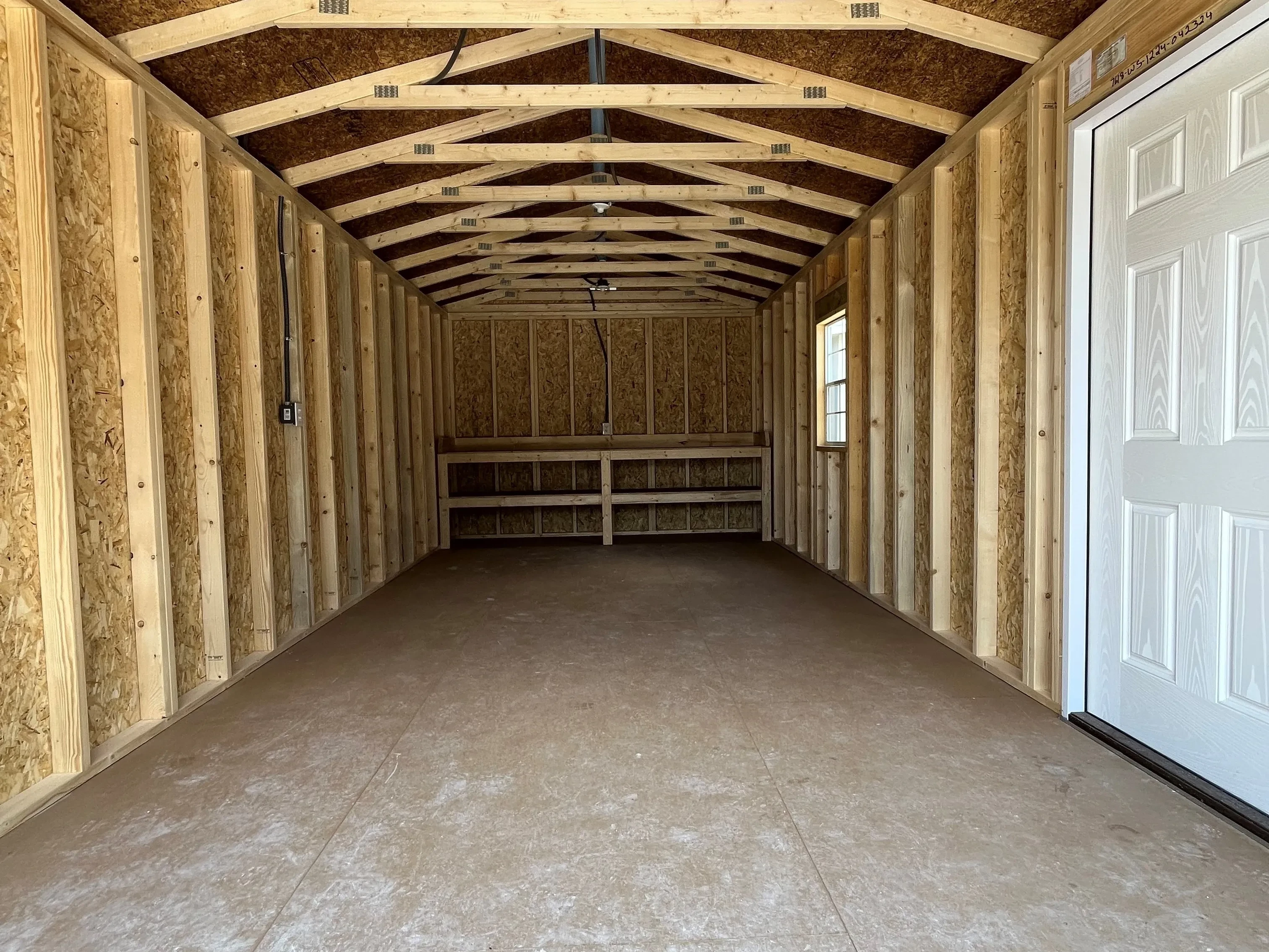 Inside view of 12x24 workshop showing entry door, window, electrical, and workbench