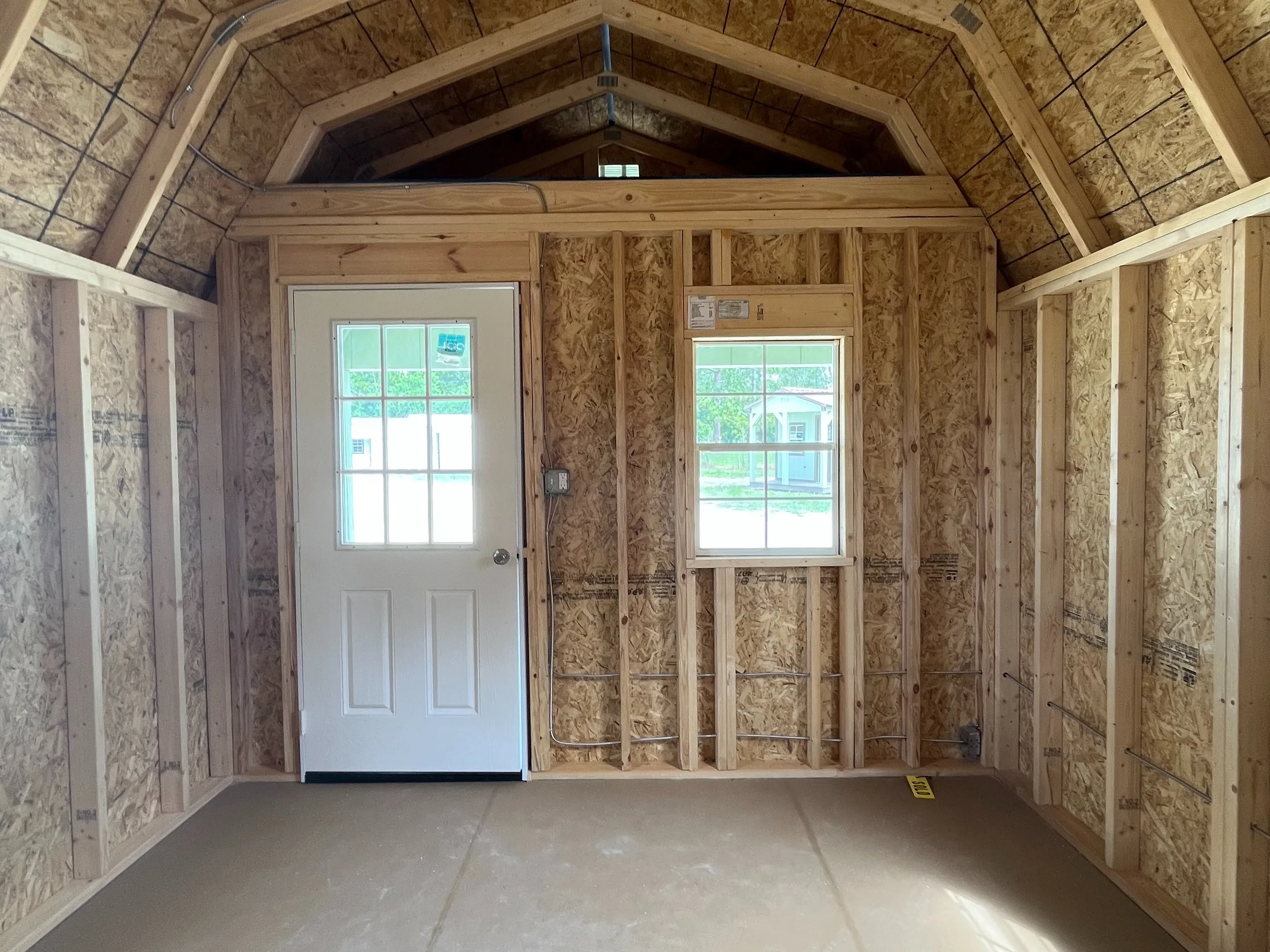 Interior of a 12x16 Lofted barn cabin showing the walk-in door and window