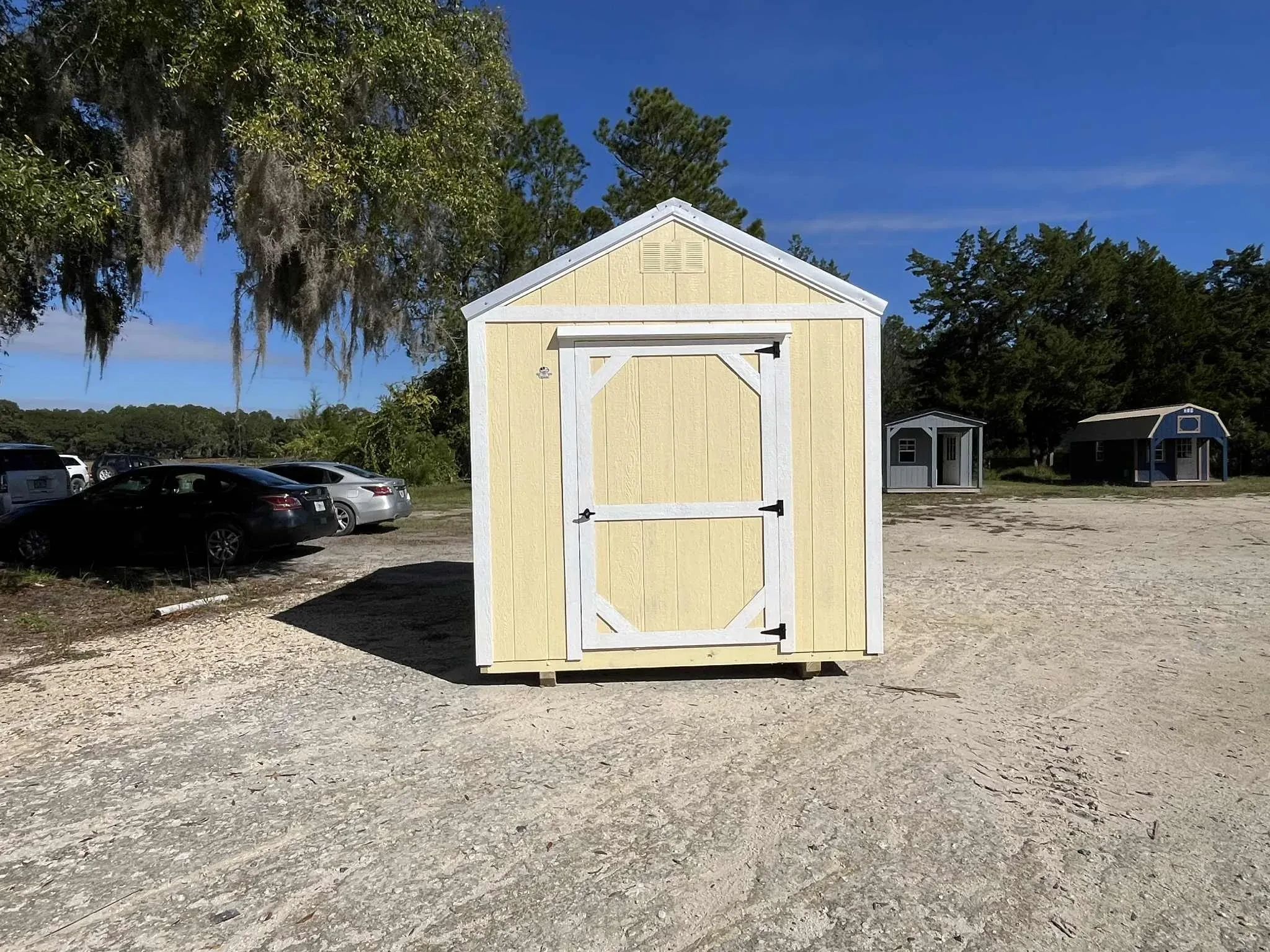 Exterior photo of a yellow with white trim 8x12 Garden Shed Economy showing entry door
