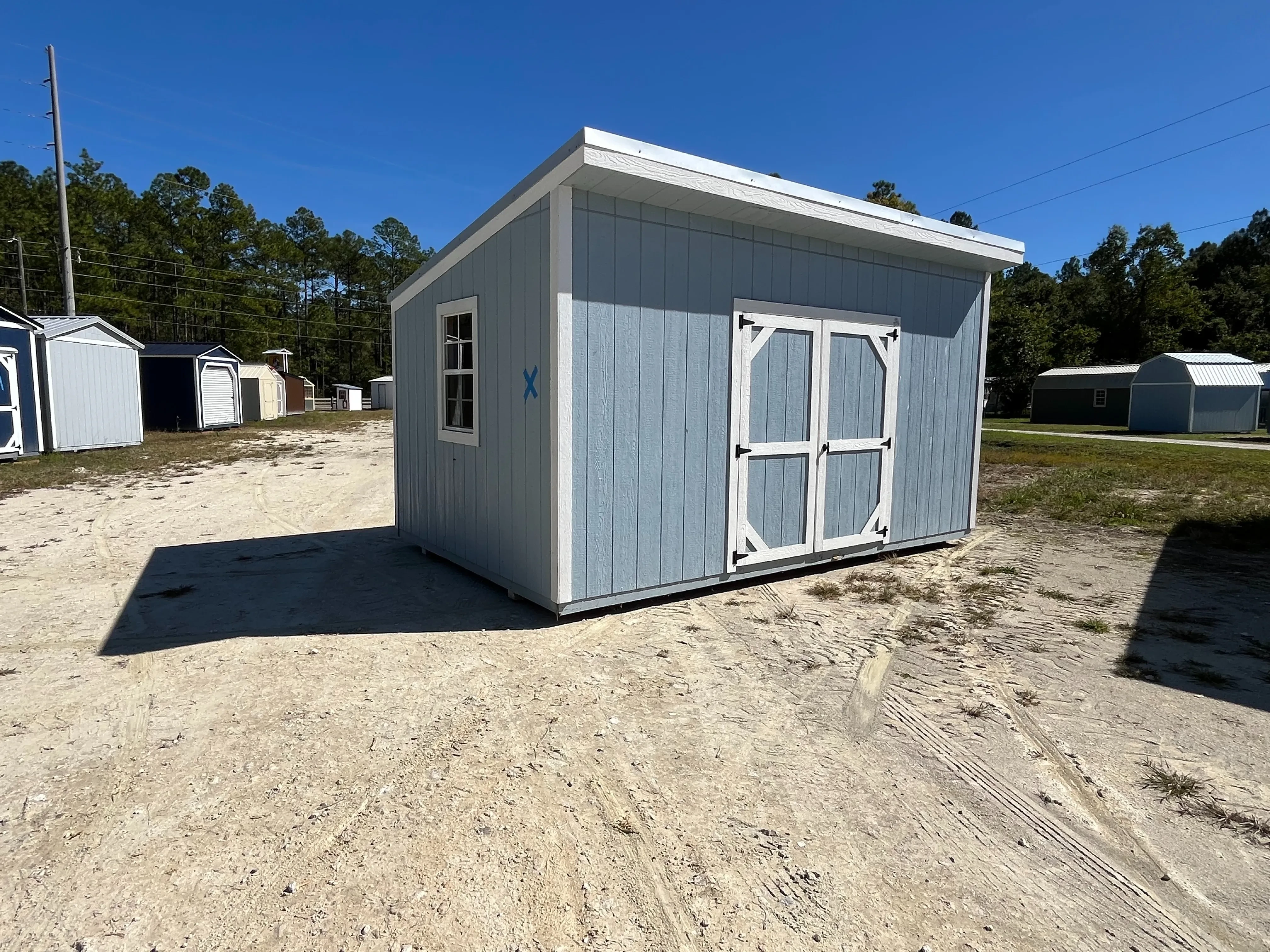 Exterior left side of a 10x16 urban shed that has a double wood door and a window