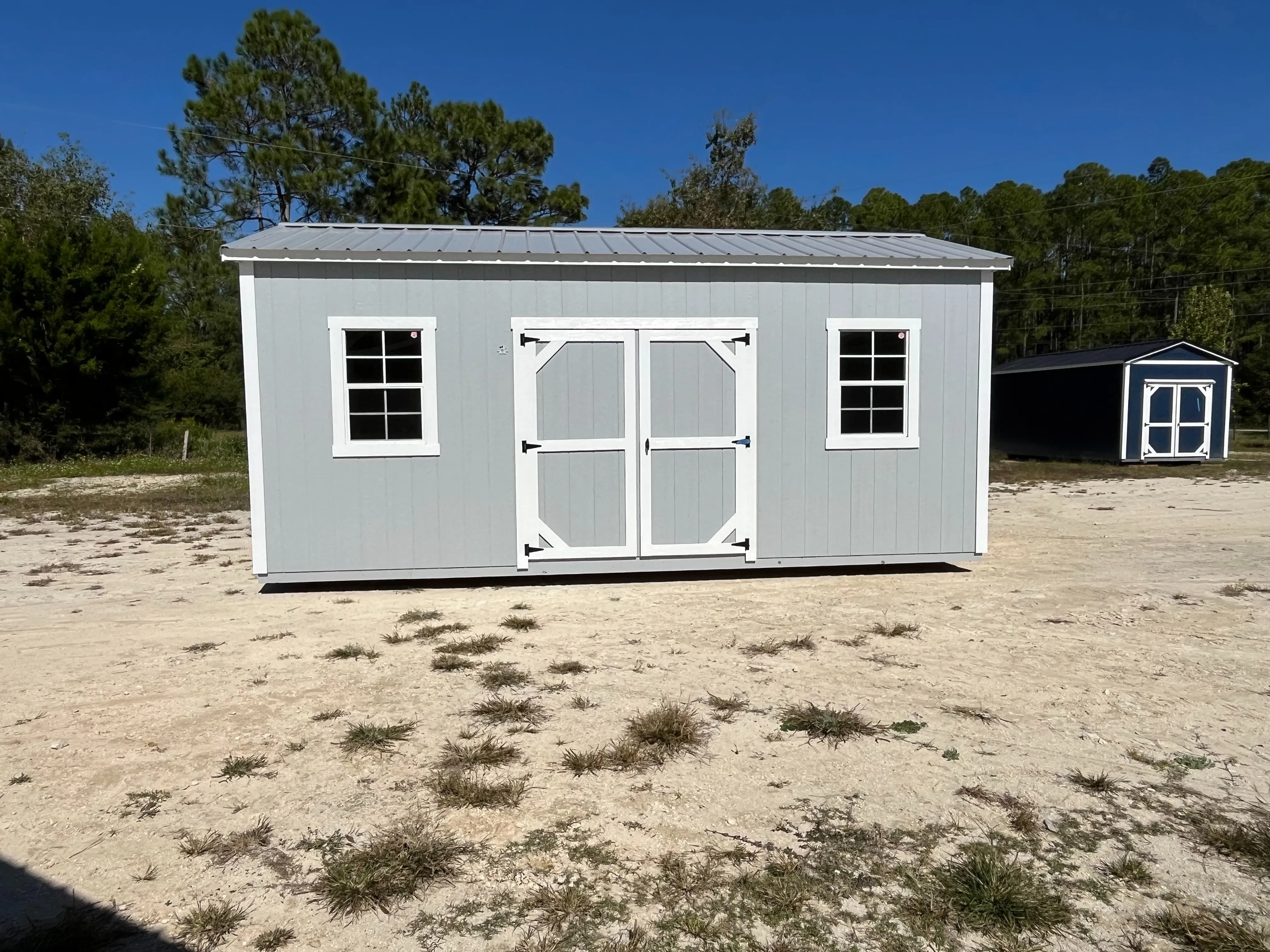 Exterior of a light grey 10x20 side garden shed with double wood doors and windows