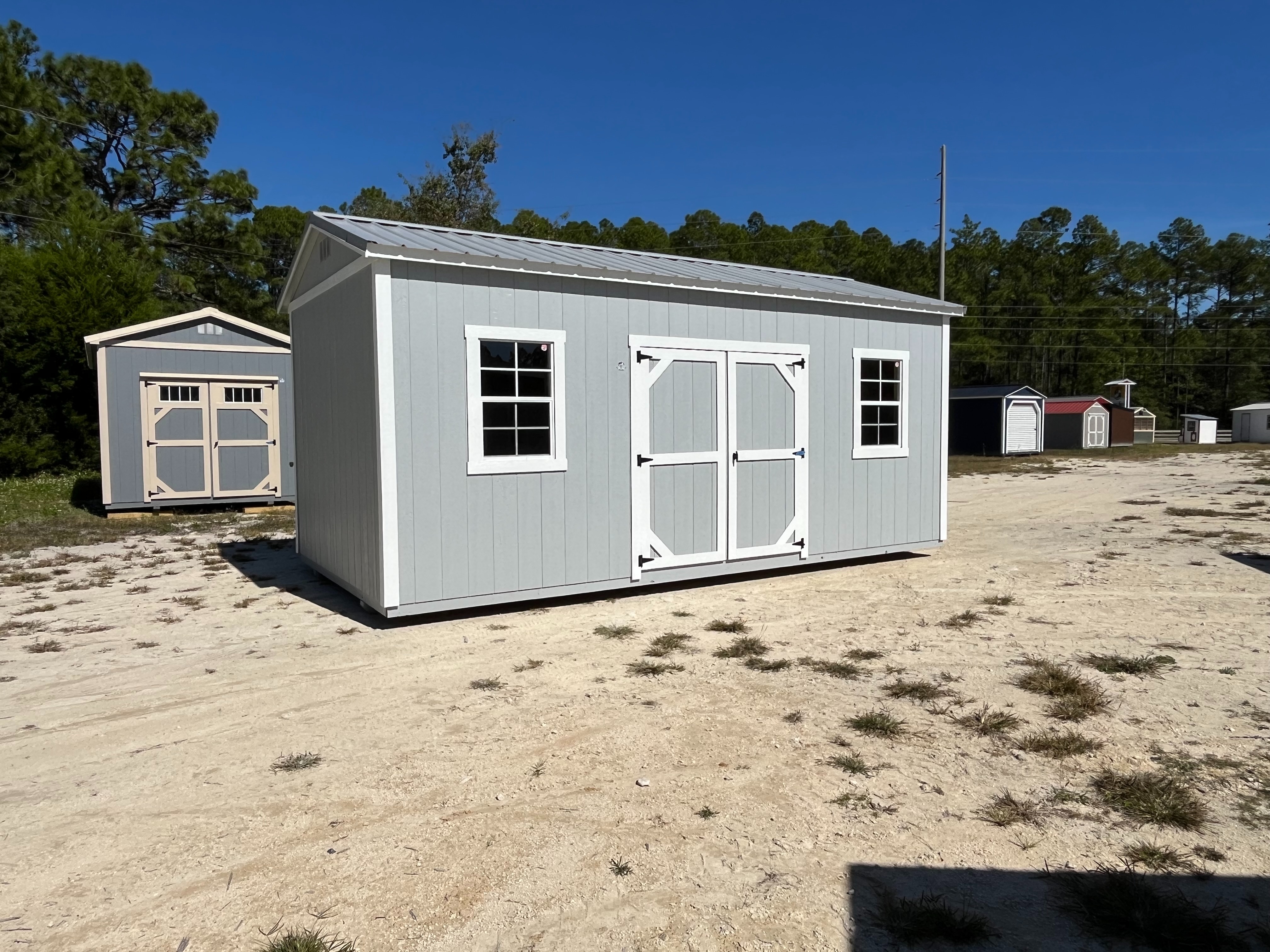 Exterior left of a light grey 10x20 side garden shed with double wood doors and windows