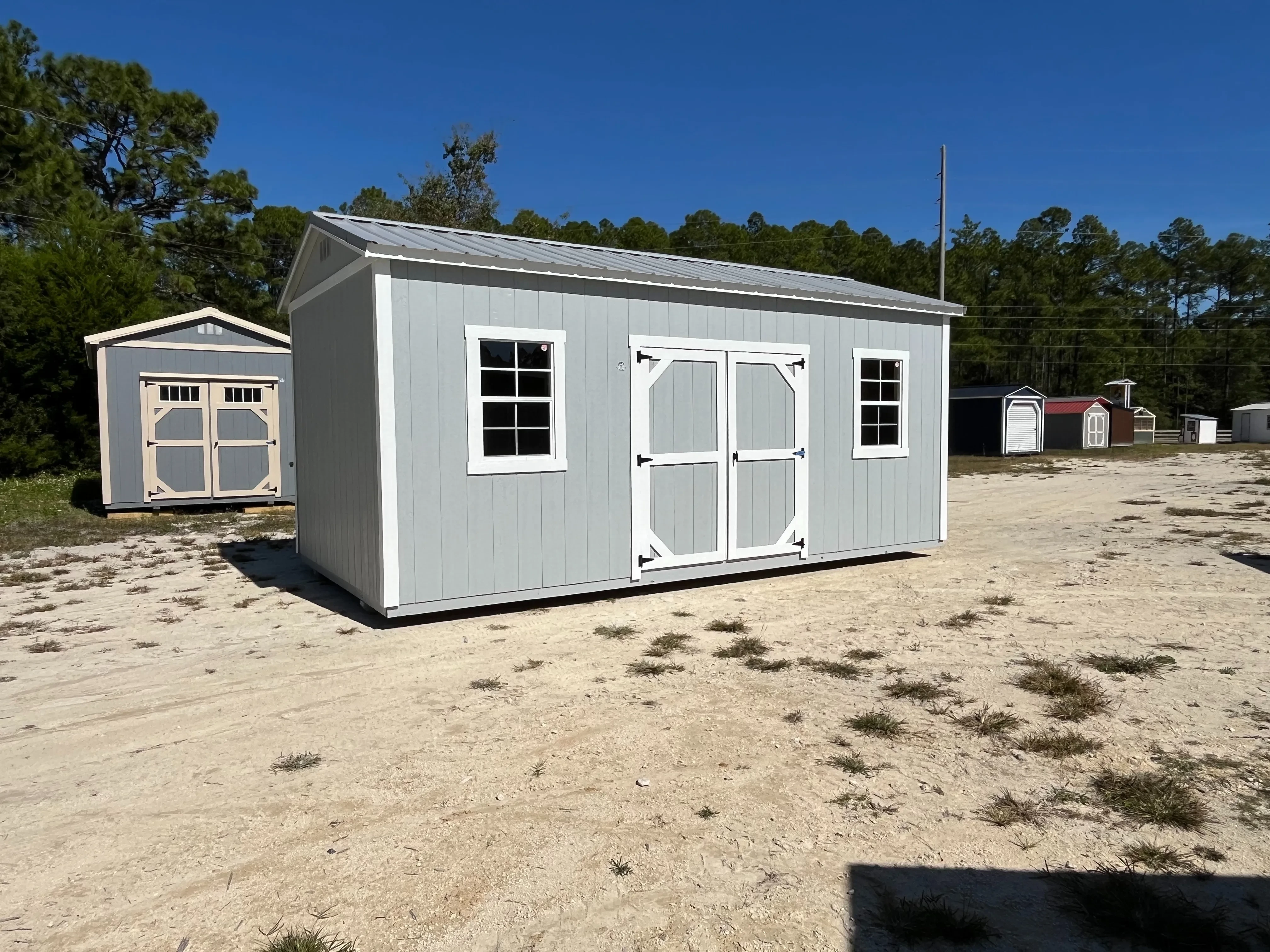 Exterior left of a light grey 10x20 side garden shed with double wood doors and windows