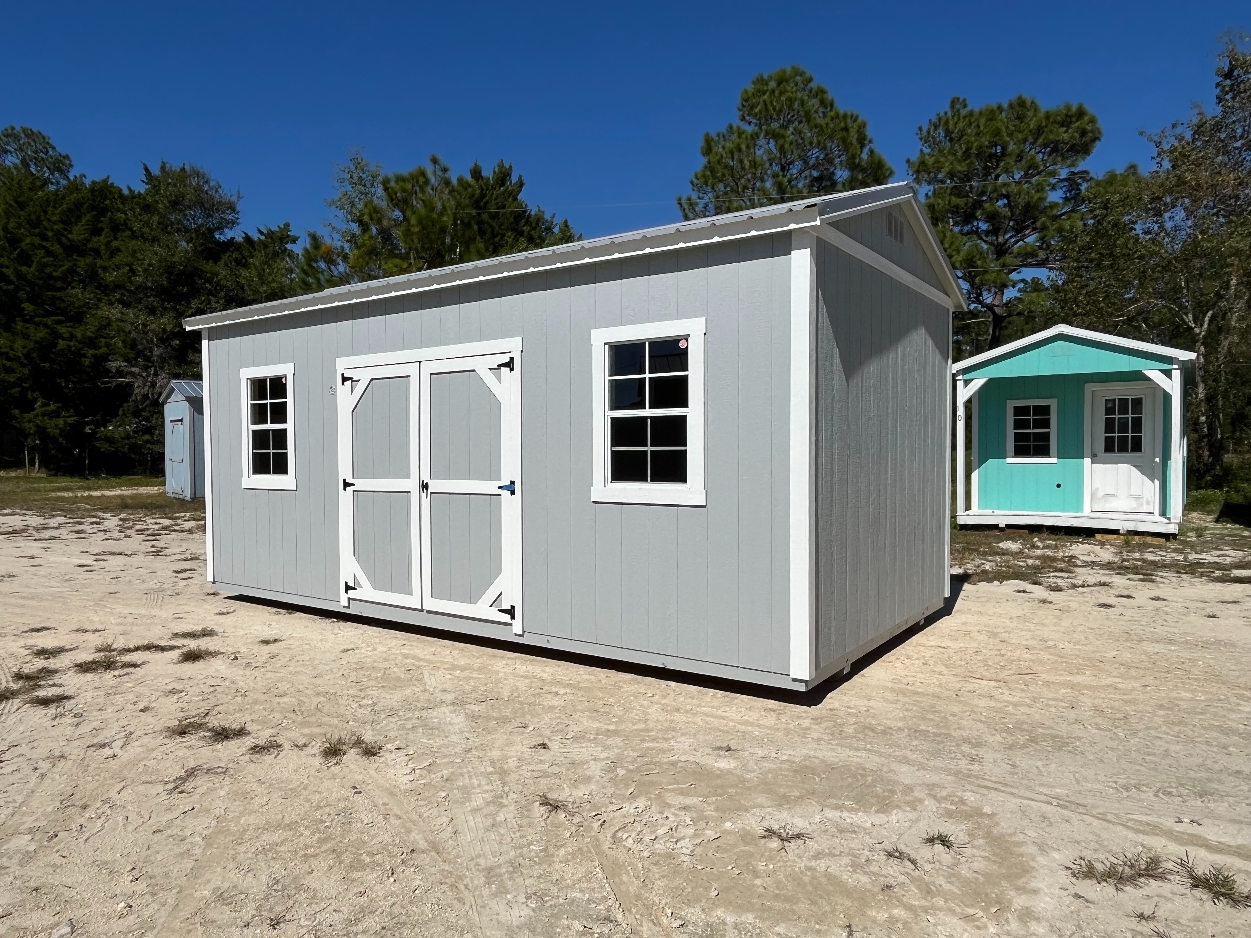 Exterior right of a light grey 10x20 side garden shed with double wood doors and windows
