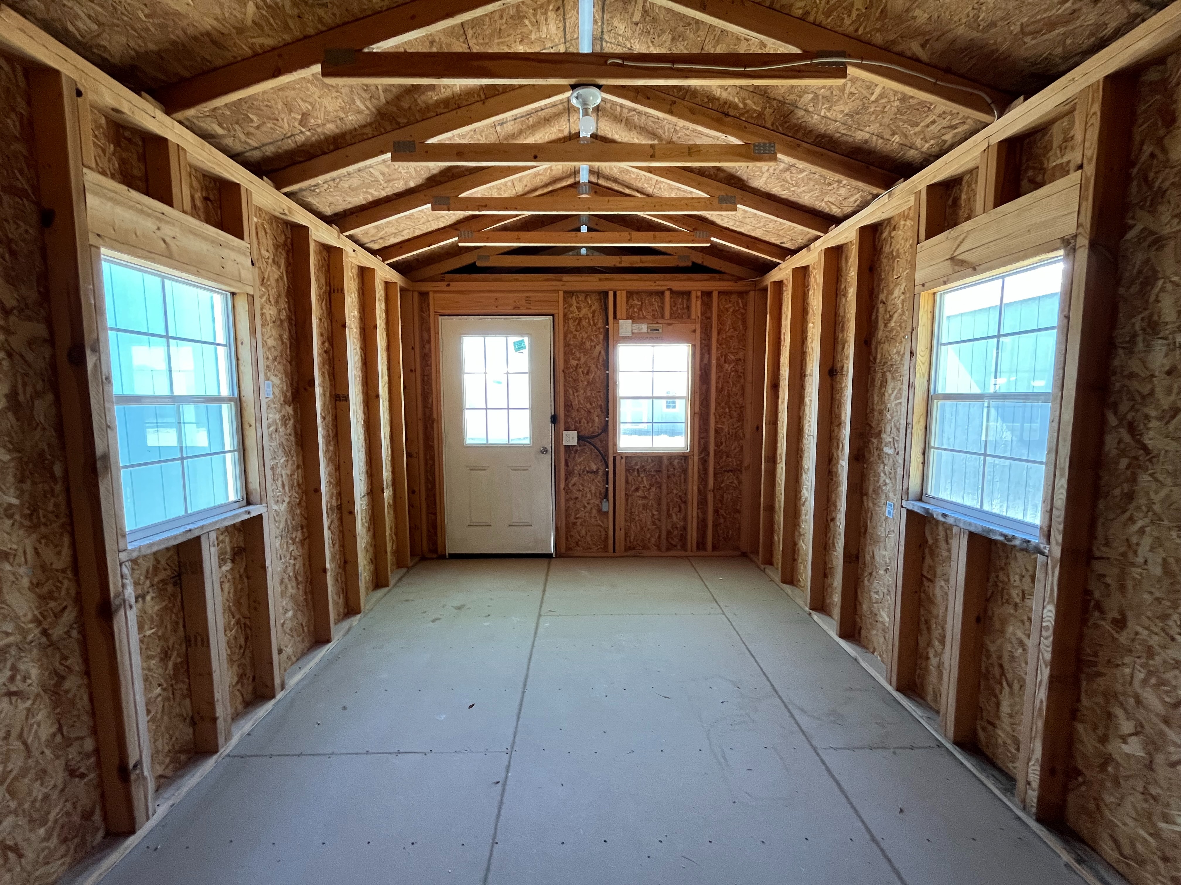 Interior of a 10x20 cabin from back wall showing walk-in door, windows and electric
