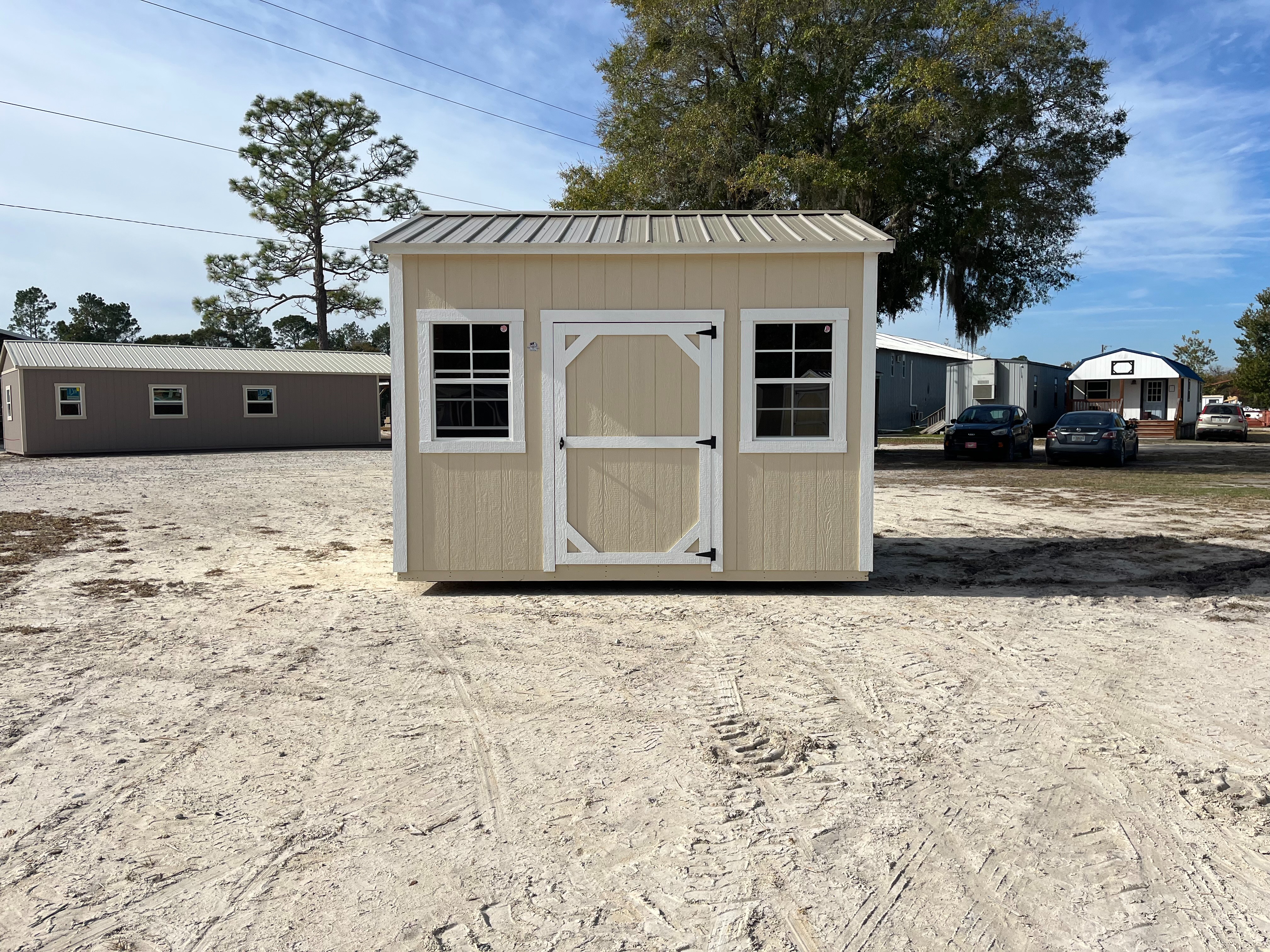 Exterior of an almond and white 10x12 side garden shed with a single wood door and windows