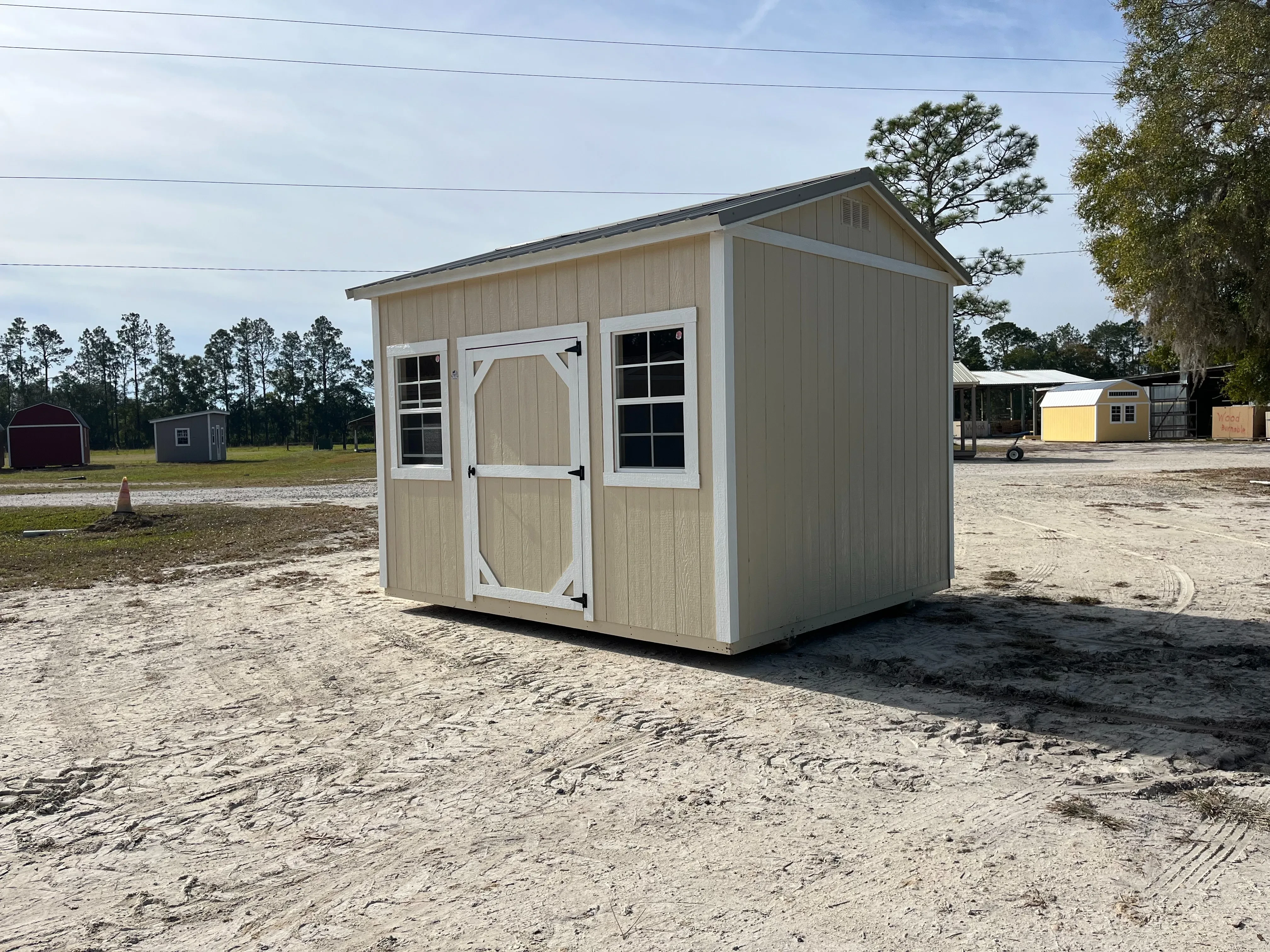 Exterior right view of an almond and white 10x12 side garden shed with a single wood door and windows