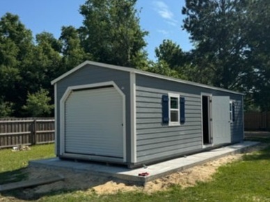 A gray workshop shed with a garage door in the end