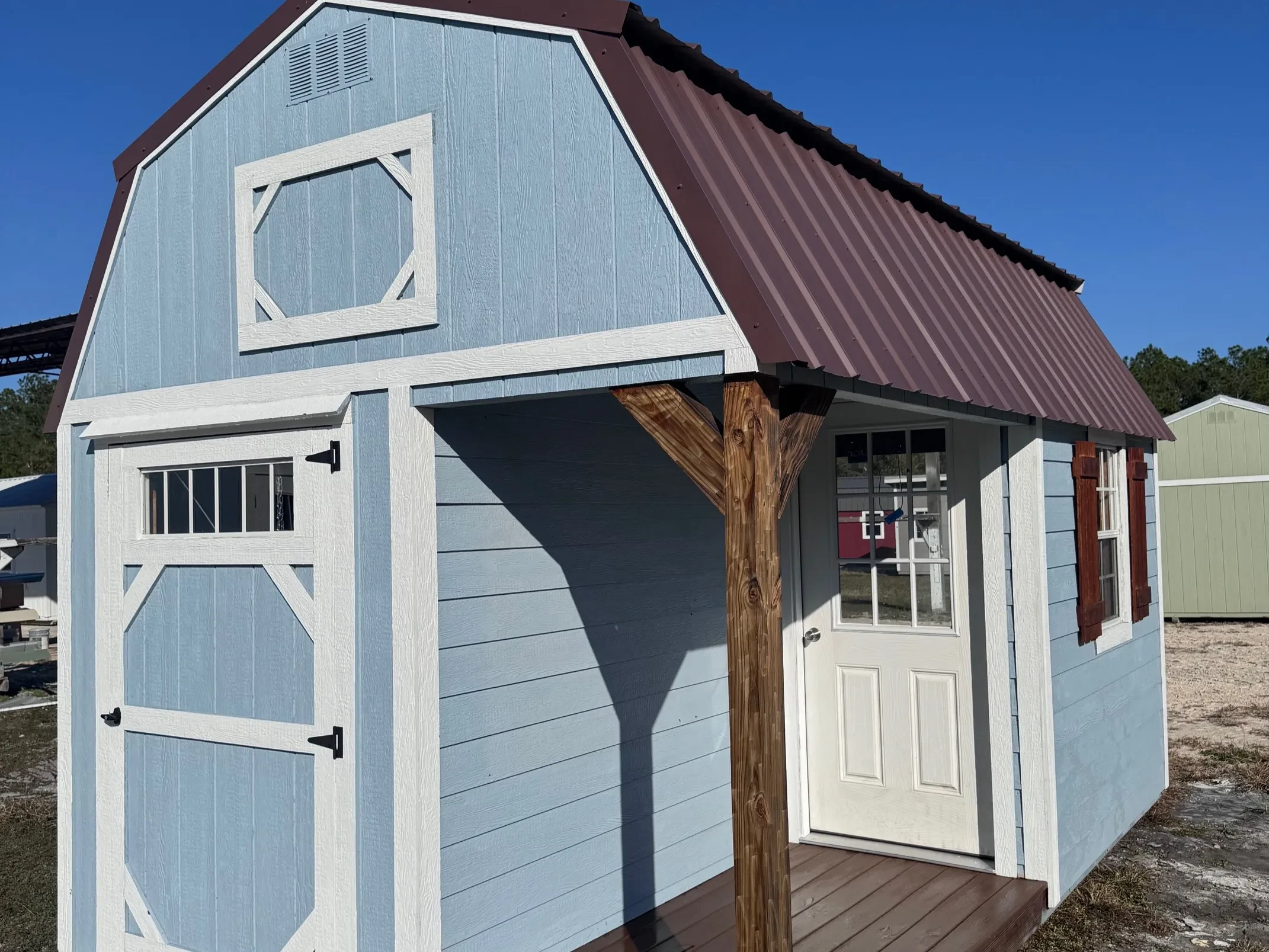 10x16 Lofted Barn Cabin with Dockside Blue siding, white trim, brown roof, porch, and shutters