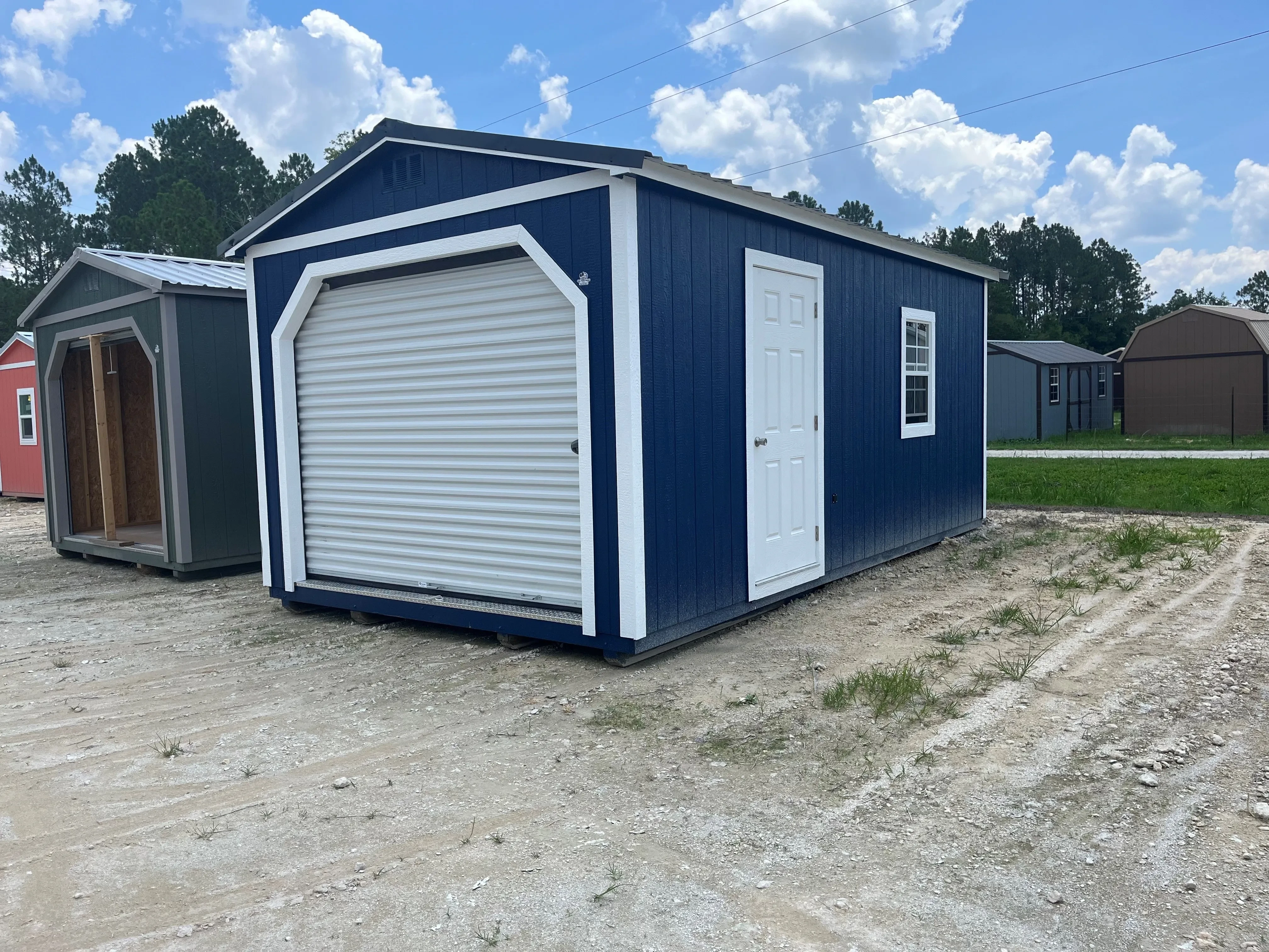 Exterior view of a dark blue 12x20 workshop with a roll up door, walk-in door and window