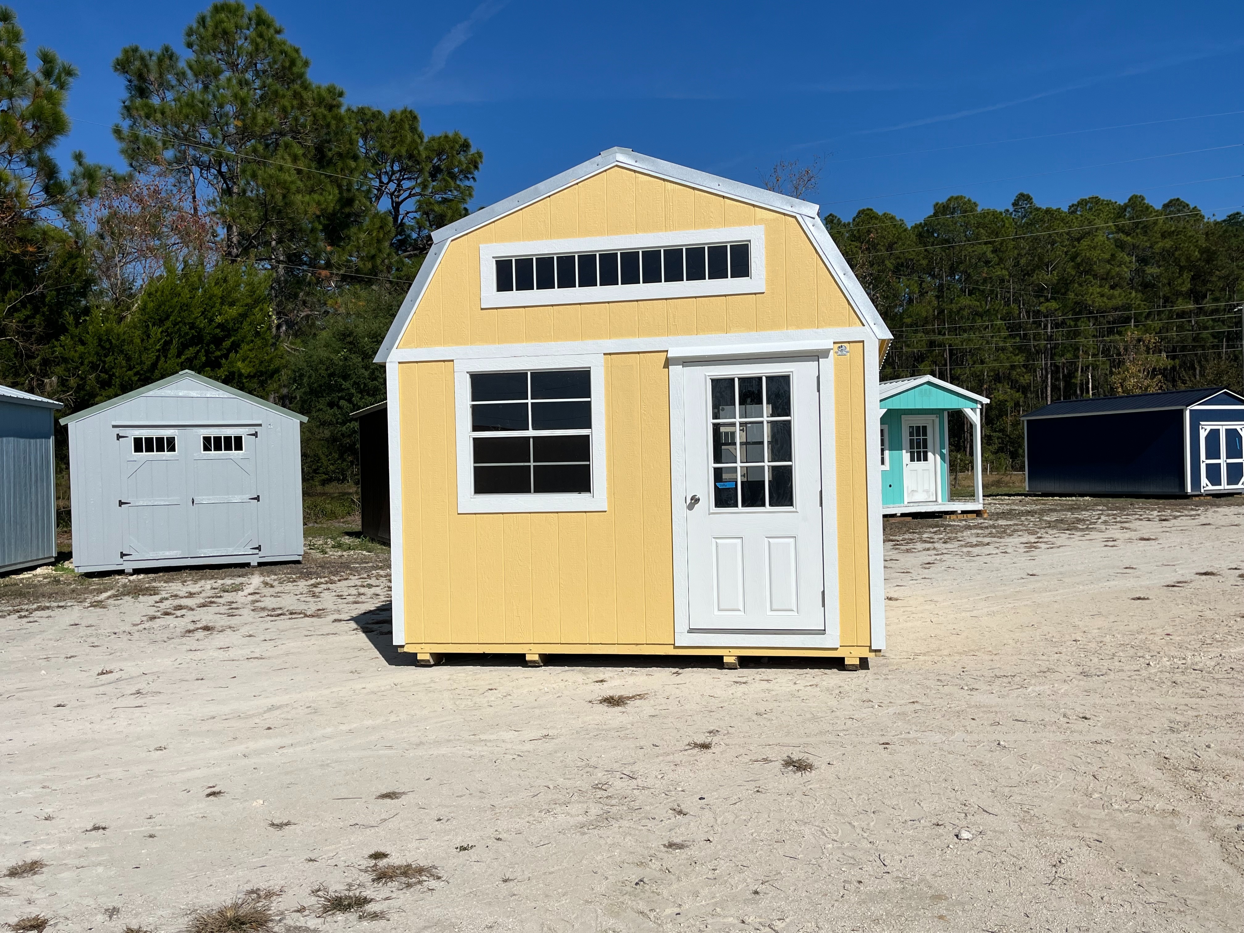 Exterior front view of a yellow 12x16 lofted barn with a walk-in door and windows