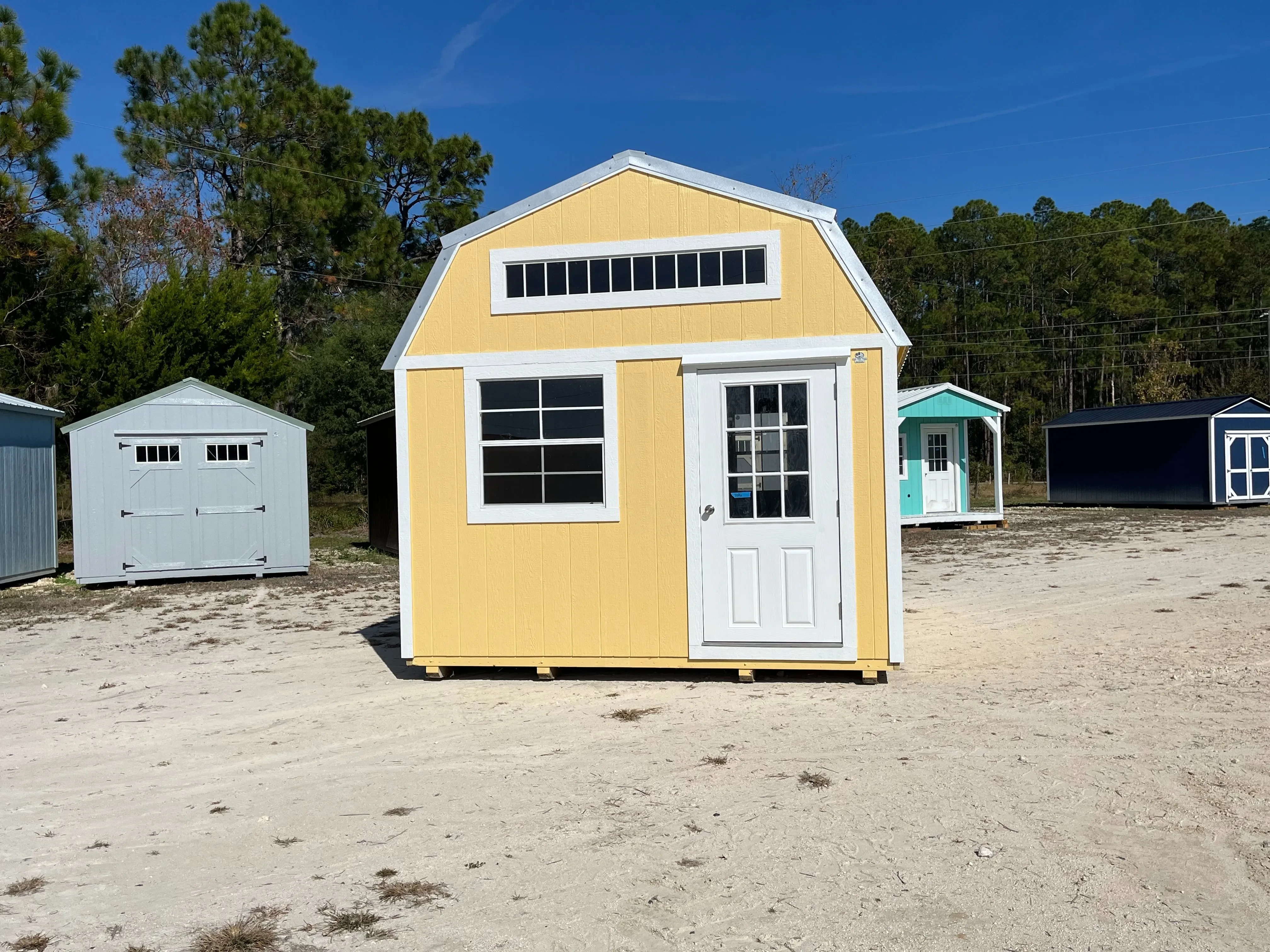 Exterior front view of a yellow 12x16 lofted barn with a walk-in door and windows