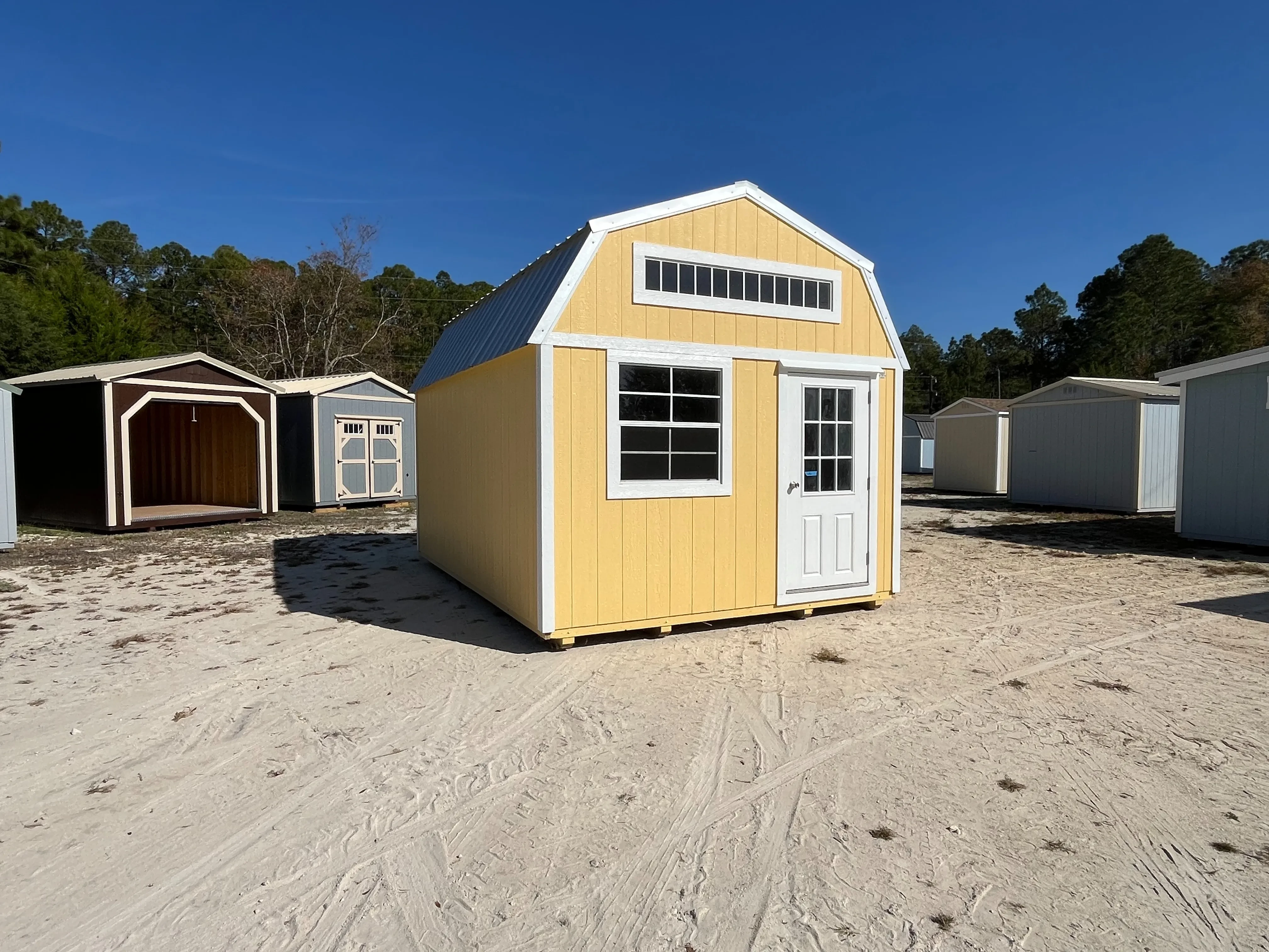 Exterior front and left side view of a yellow 12x16 lofted barn with a walk-in door and windows
