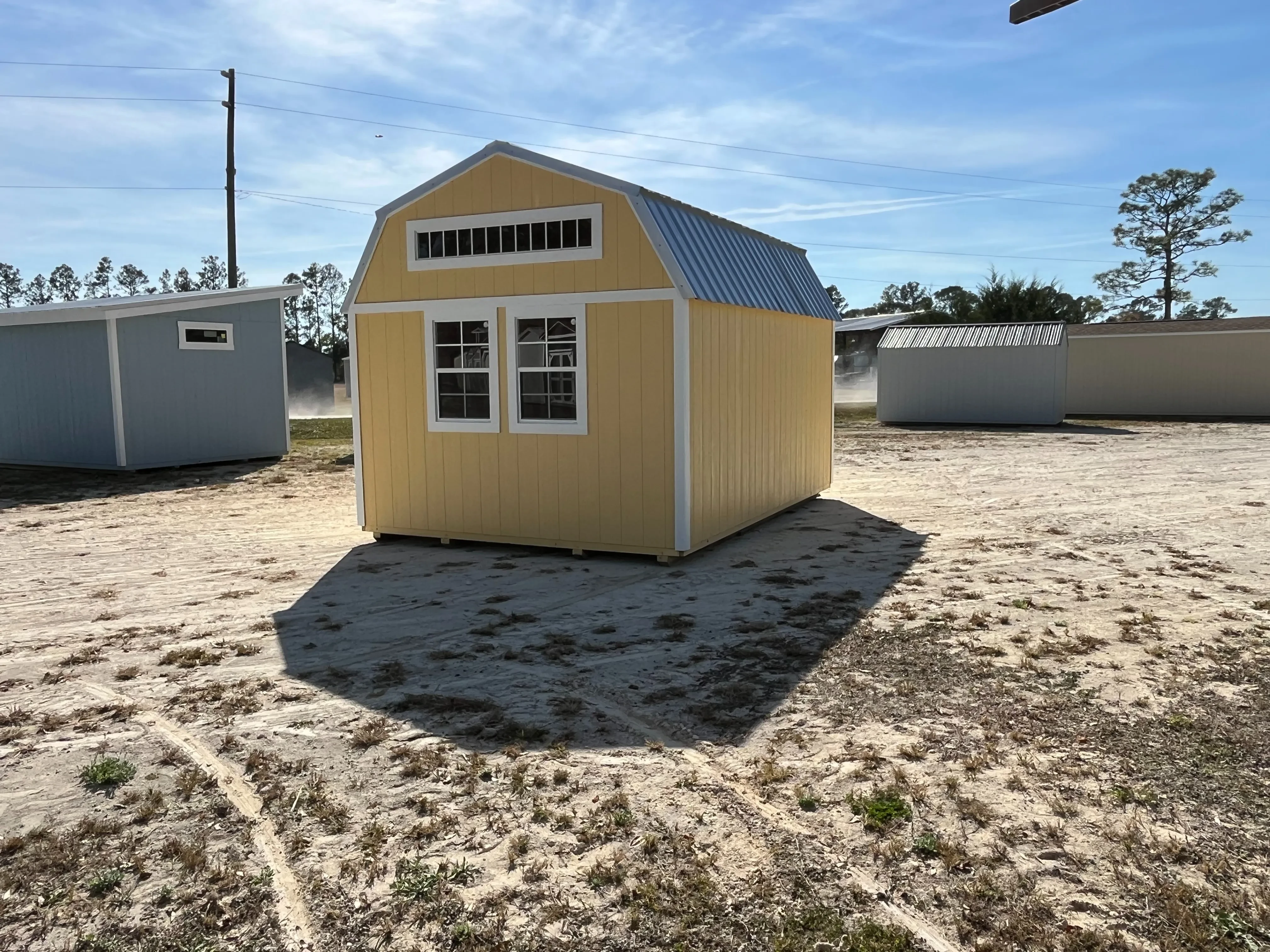 Exterior rear view of a yellow 12x16 lofted barn with windows